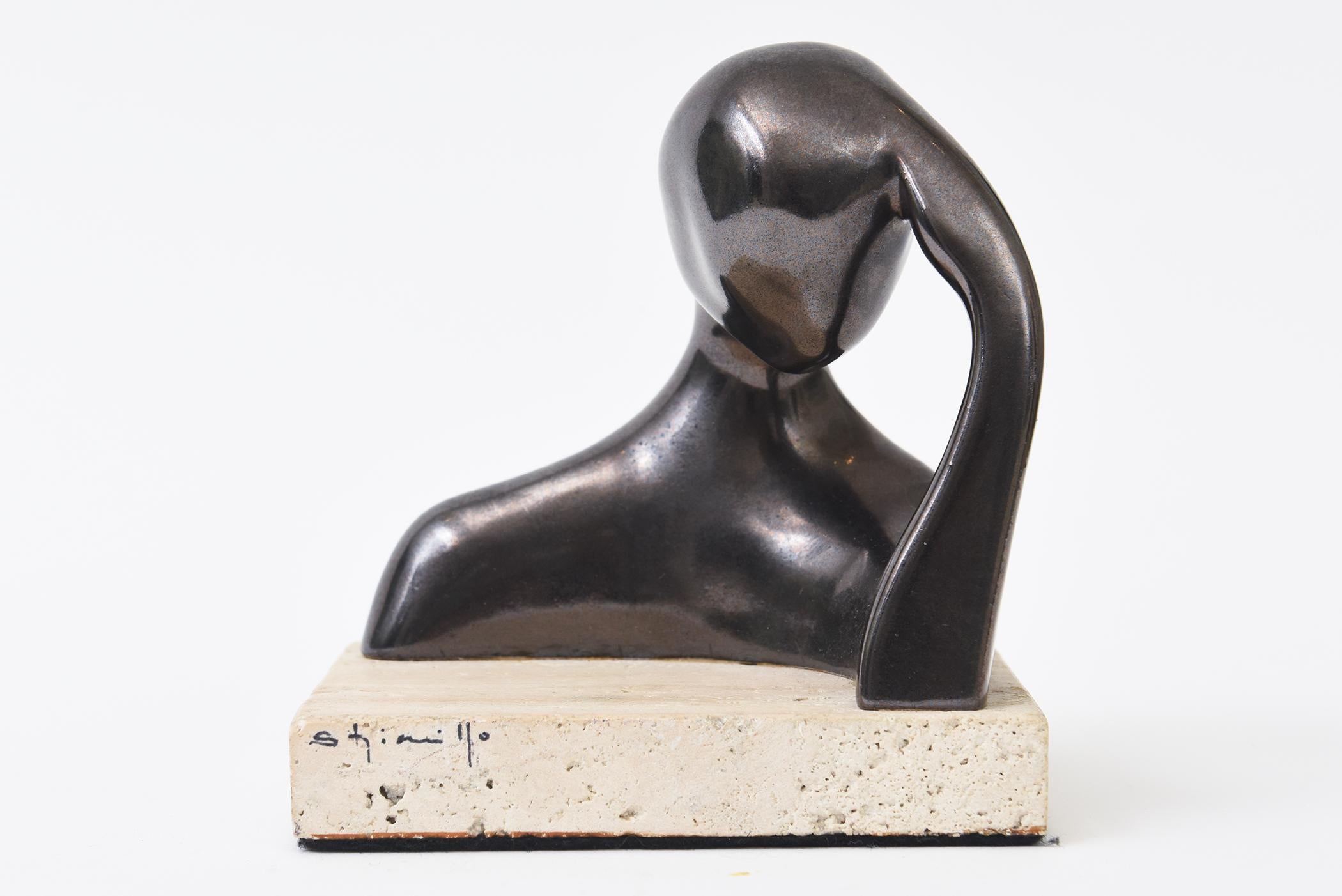 Questa scultura firmata a tecnica mista è in ceramica con finitura metallica bronzata e poggia su una base in travertino firmata. Si tratta di un busto femminile contemplativo in riposo.
Si legge Stimi 1-0 ma è semi illeggibile. Dagli anni '90. Da