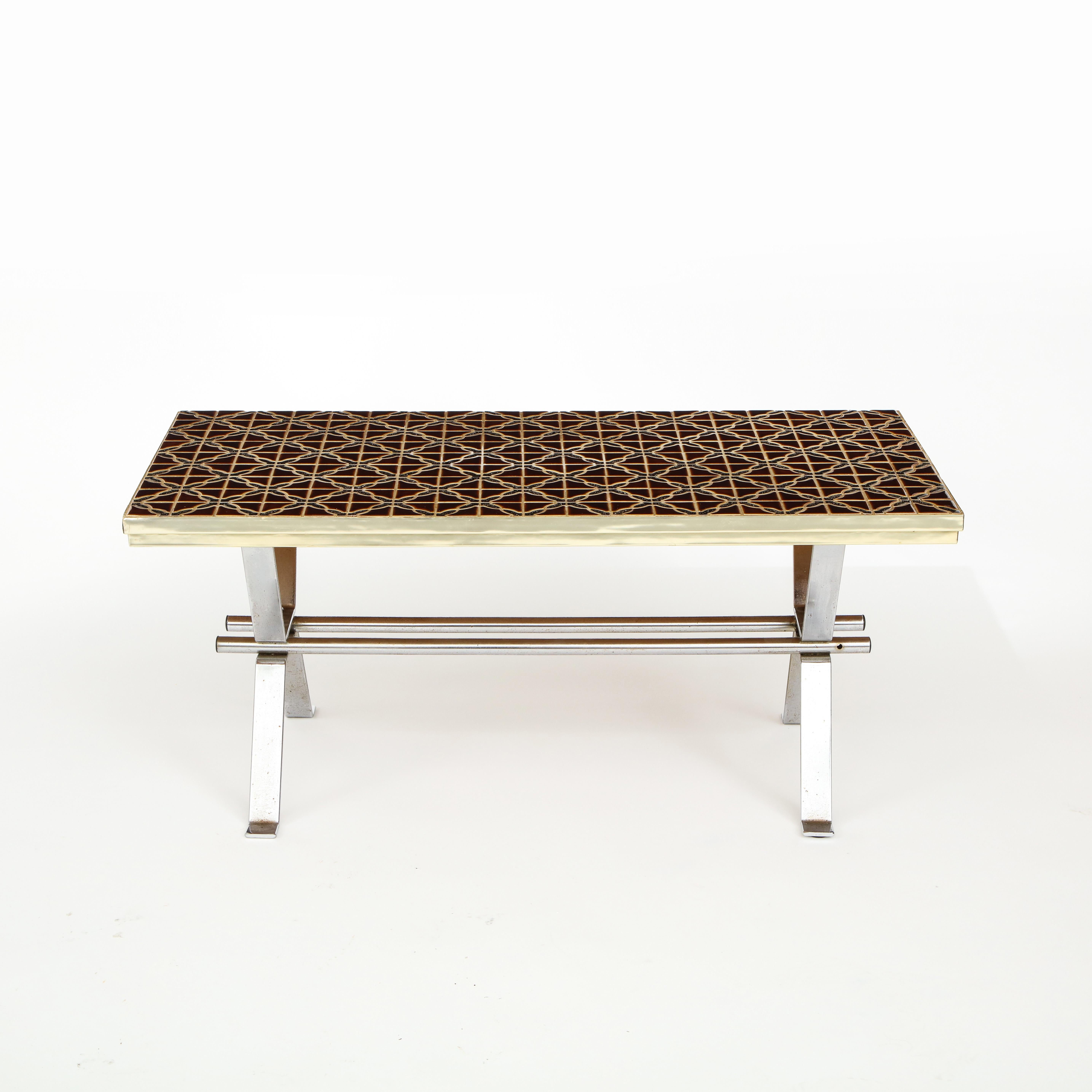 Handsome table with a mosaic top. Geometric pattern rendered in a rich glaze. Brass banding frames the top. An elegant metal base is in a contrasting finish.