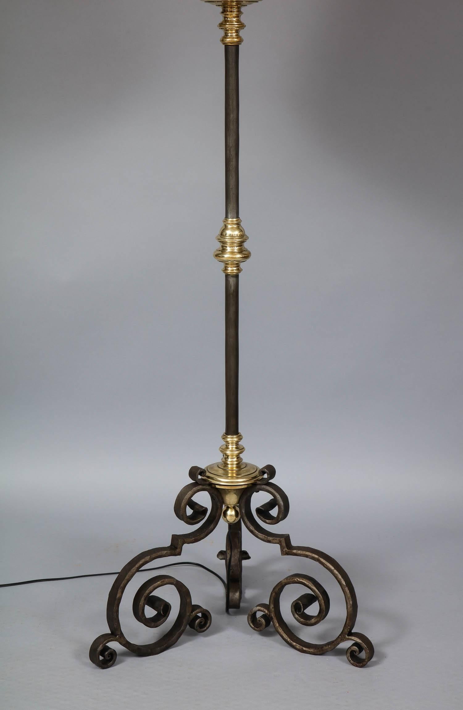 Fine wrought iron and brass Baroque style floor lamp having patinated iron shaft with turned brass collars, the base having scrolled form, the whole of pleasing proportion.
