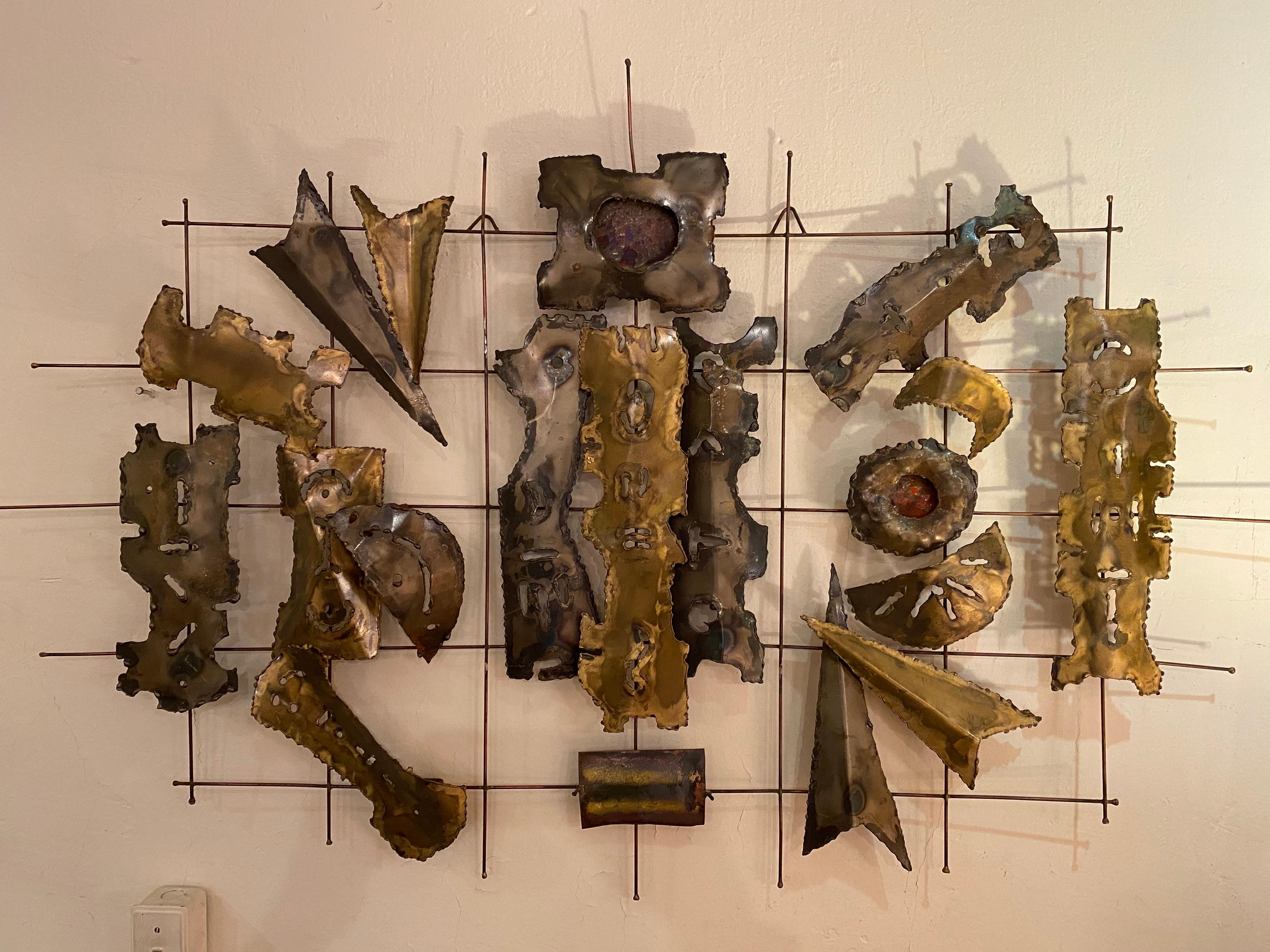 Mixed metal wall sculpture. Abstract cut out shapes mounted to a wire grid. Nice size and scale. Metals appear to be brass, copper with applied metal overlays.