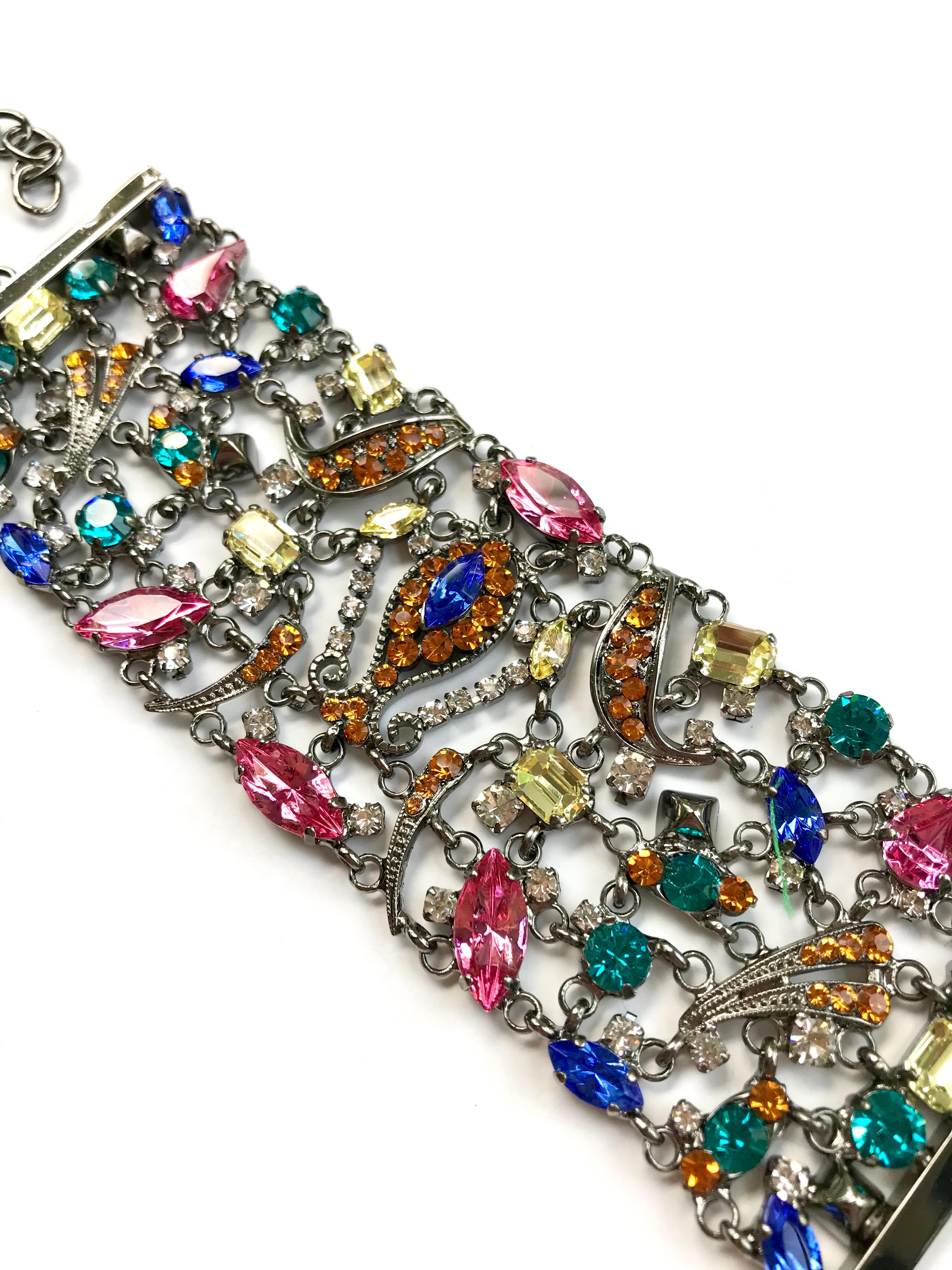 Beautiful statement fashion jewelry bracelet, showcasing mixed cut multi color crystals in cobalt blue, pink, green, yellow, orange and clear, set in an intricately open work design on pewter gray metal. Made in Florence by local artisans which have
