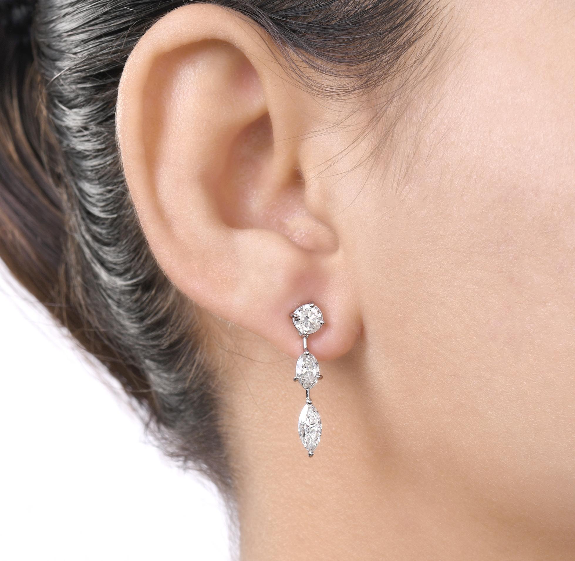 Questi orecchini pendenti con diamanti di forma mista in oro bianco 14 carati presentano diamanti di taglio rotondo, ovale e marquise incastonati uno sotto l'altro nell'ordine: rotondo in cima, ovale in mezzo e marquise che penzolano in basso. 
I