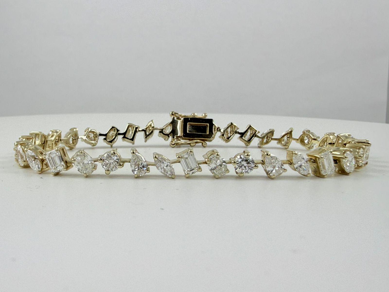 Ce bracelet de tennis sophistiqué présente un mélange captivant de diamants de taille émeraude et de diamants ronds de taille brillant, savamment disposés en alternance. Fabriqué en or jaune 14 carats, le bracelet présente un poids total de diamants