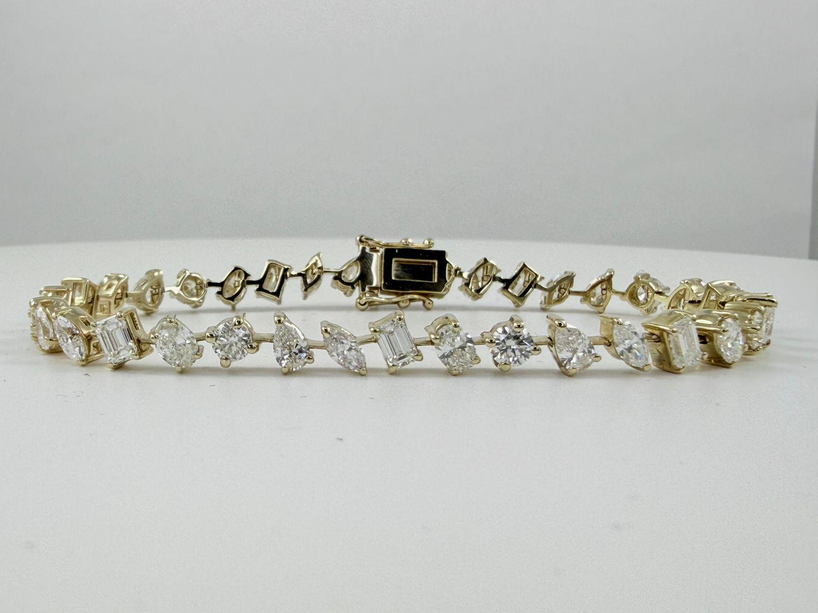 Ce bracelet de tennis sophistiqué présente un mélange captivant de diamants de taille émeraude et de diamants ronds de taille brillant, savamment disposés en alternance. Fabriqué en or jaune 14 carats, le bracelet présente un poids total de diamants