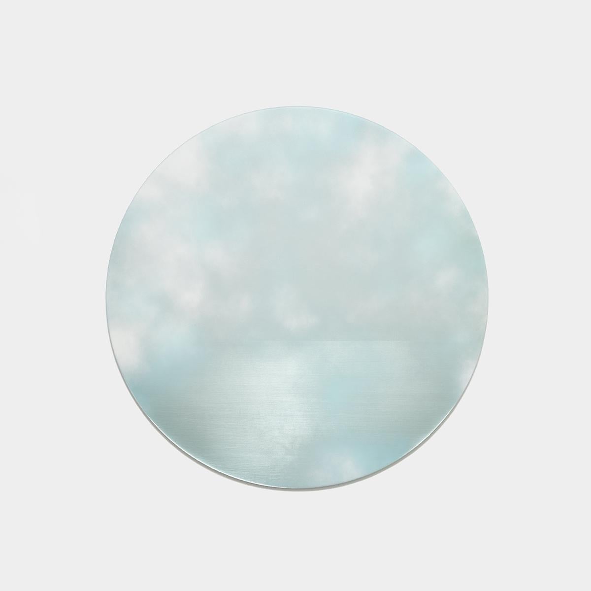 Reflective round painting of clouds in a pale blue sky