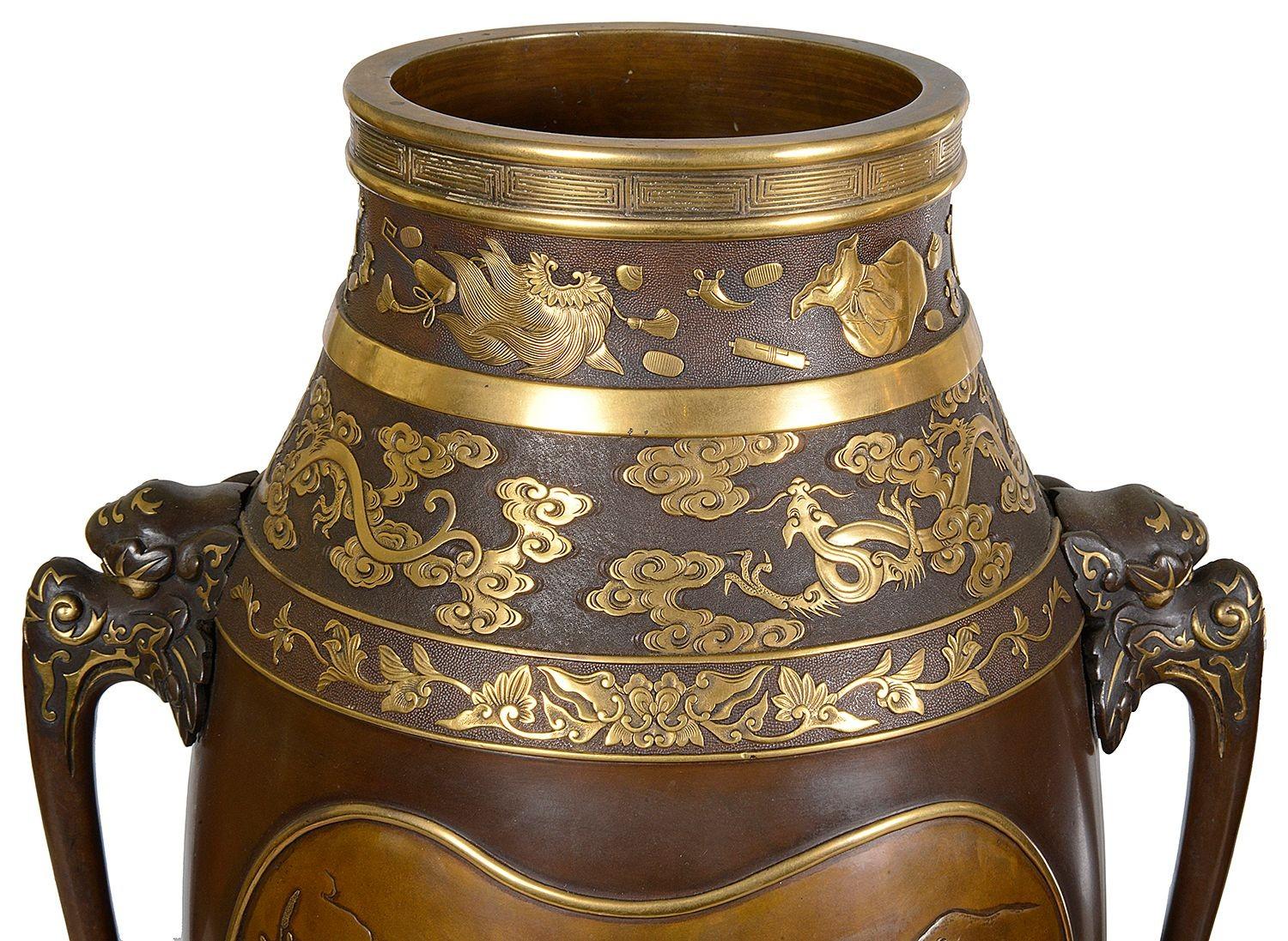 This exquisite pair of Miyao Japanese bronze vases features a classic tapering form with rich dark patina and intricate gold inlays. Each vase showcases detailed reliefs of natural scenes, highlighting traditional motifs that symbolize harmony and