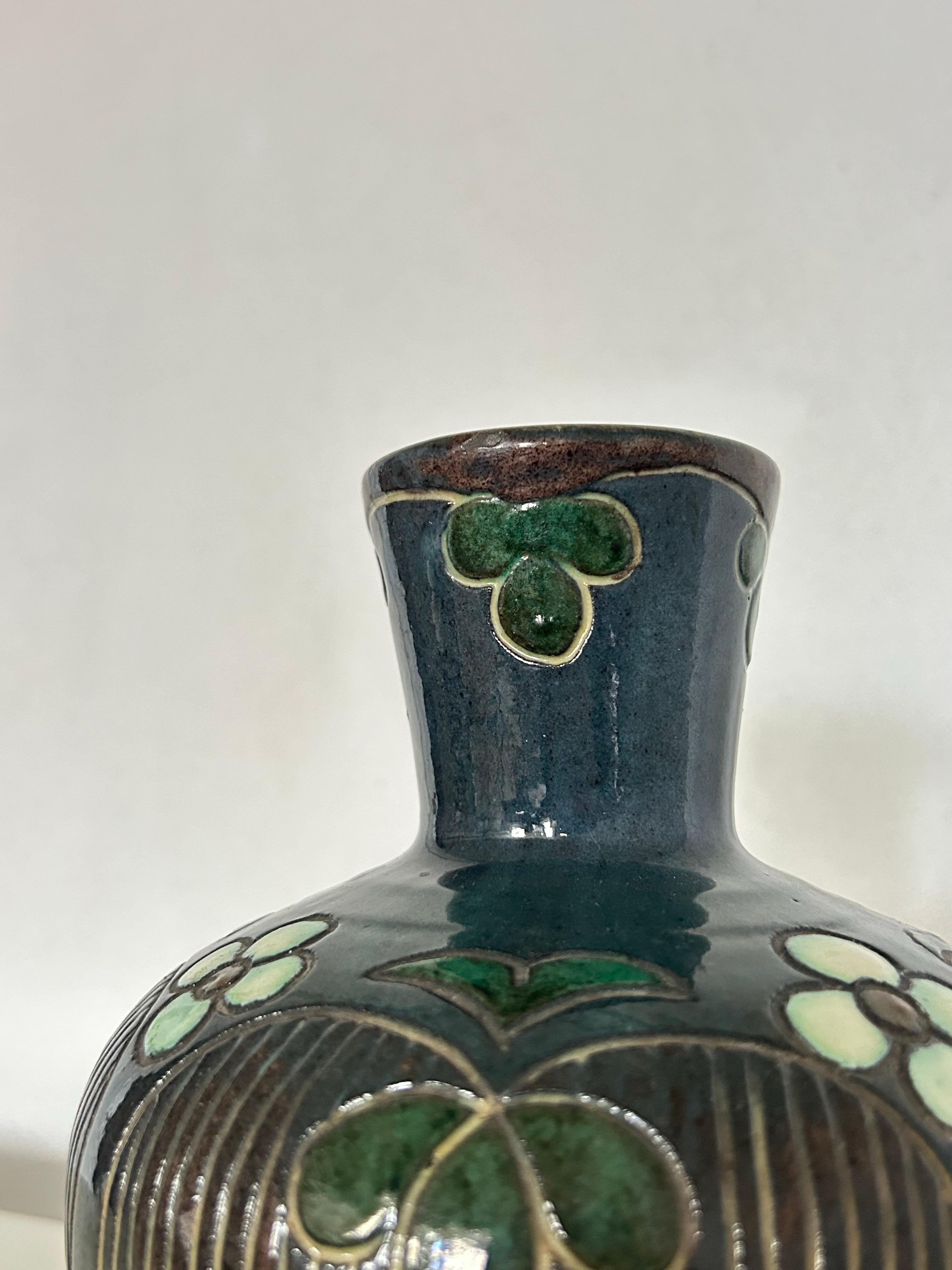 Rare vase Art nouveau de l'atelier de céramique danois Møller & Bøgely (actif de 1917 à 1920), présentant un magnifique motif floral dentelé avec une subtile décoration rayée sous certaines fleurs. Le vase est émaillé dans des tons harmonieux de