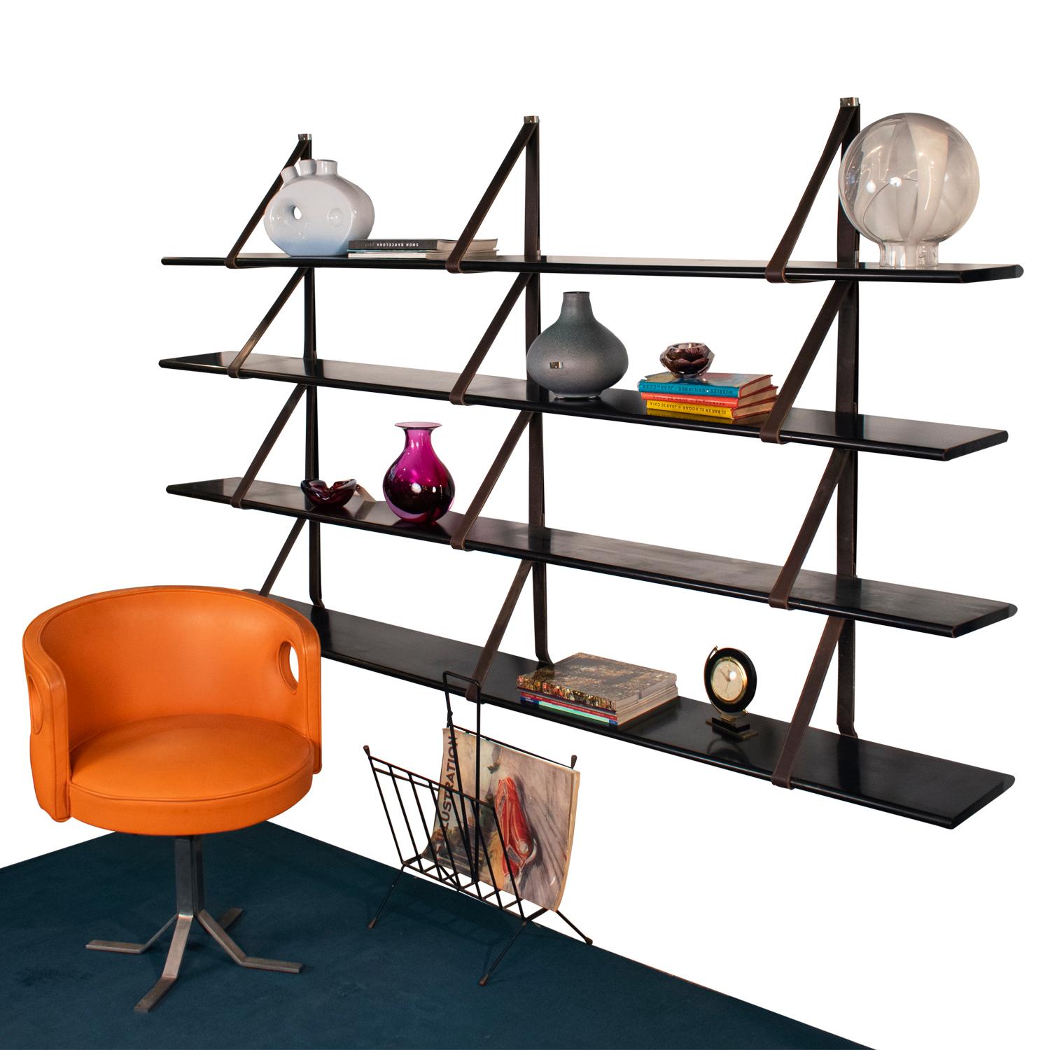 MM wall-mounted bookshelf designed by Miguel Milá for Gres in 1962, Spain.
Shelves attached by leather straps. The shelves measure: 225cm in length by 25 cm. deep and 2.5 cm. thick.
Shelves are in dark wood veneer dm. The shelves are hung on the