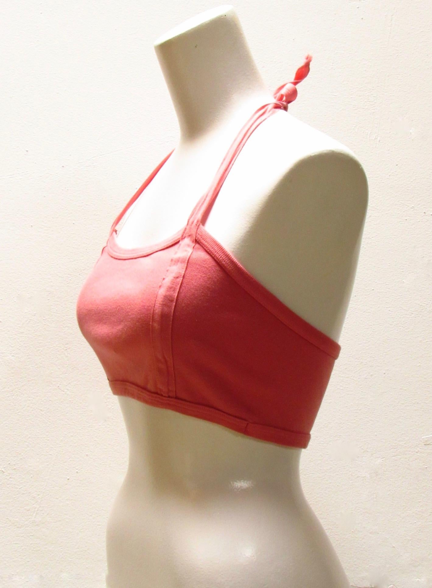 Soft cotton cropped halter top in coral comes from Maison Martin Margiela. It's straps, which secure around the neck, run down the length of the front of the top. 
