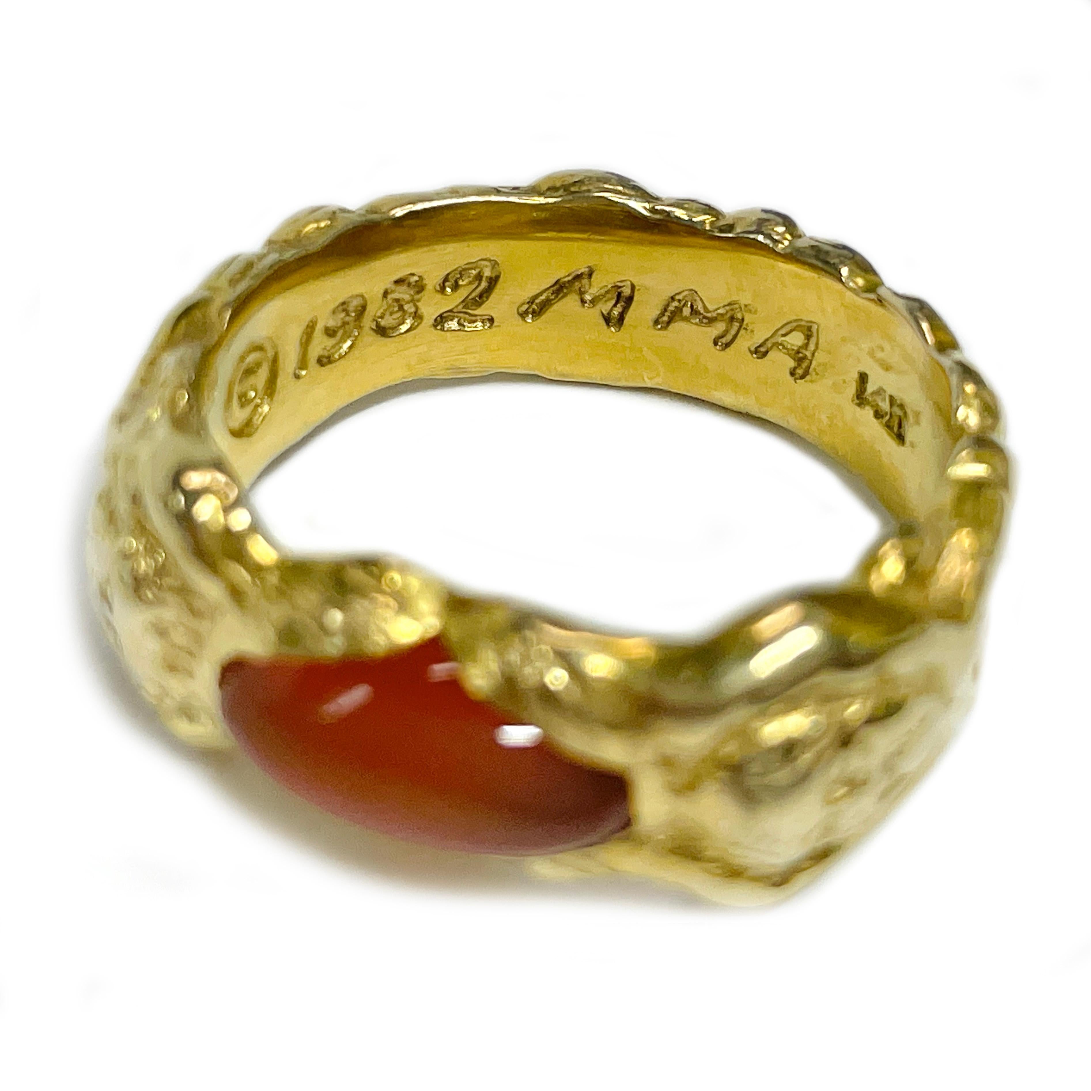 14 Karat Yellow Gold Carnelian Nugget Metropolitan Museum of Art (MMA) Ring. The ring features an oval 11 x 5.7mm Carnelian cabochon bezel-set with a lion head on each side of the band and an overall nugget texture. The oval dome-shaped cabochon is