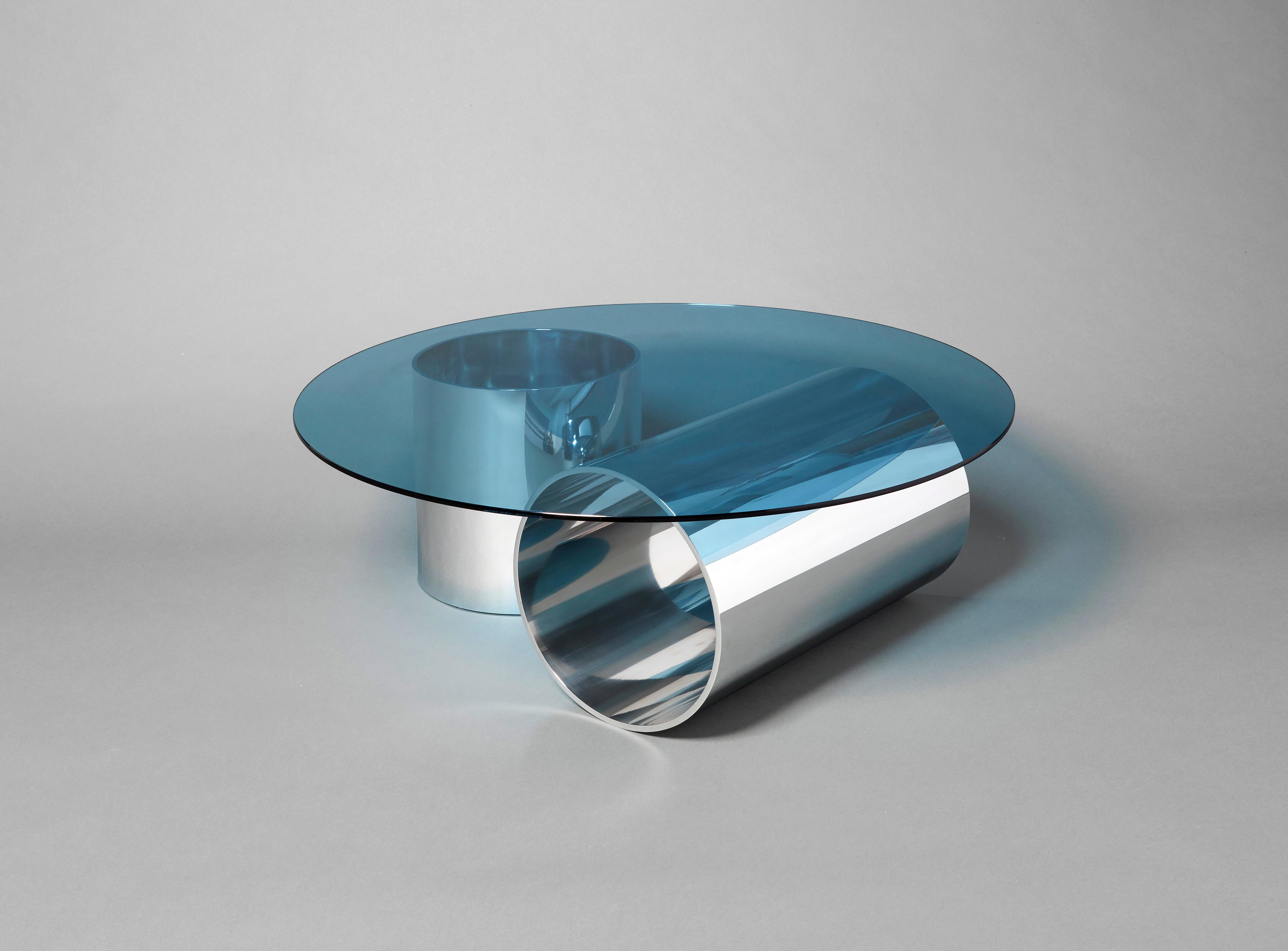 'MMPM' Tubular polished aluminium and blue tinted glass coffee table.

This design further explores the designers obsession with tubular metal and graphical form. Still in his trademark minimal style, these tables are crafted in hand-polished