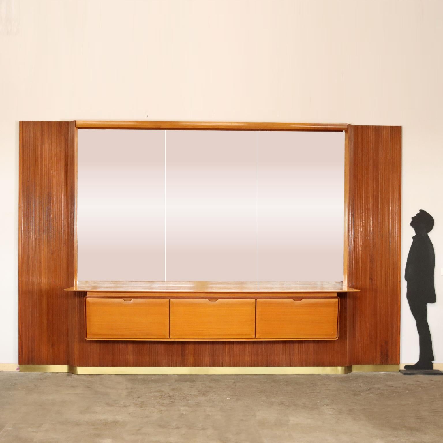 Importante mueble salón de pared de fabricación italiana del siglo XX. Realizado en caoba rubia, presenta paneles de madera de grissin, un gran espejo central y un bufé con tres puertas batientes con estantes de cristal en el interior. Adornado con