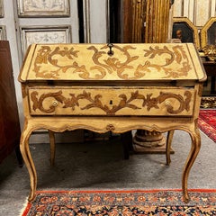 Lacquered wooden cabinet with a drop-down door, decorated with plant scrolls, Italy