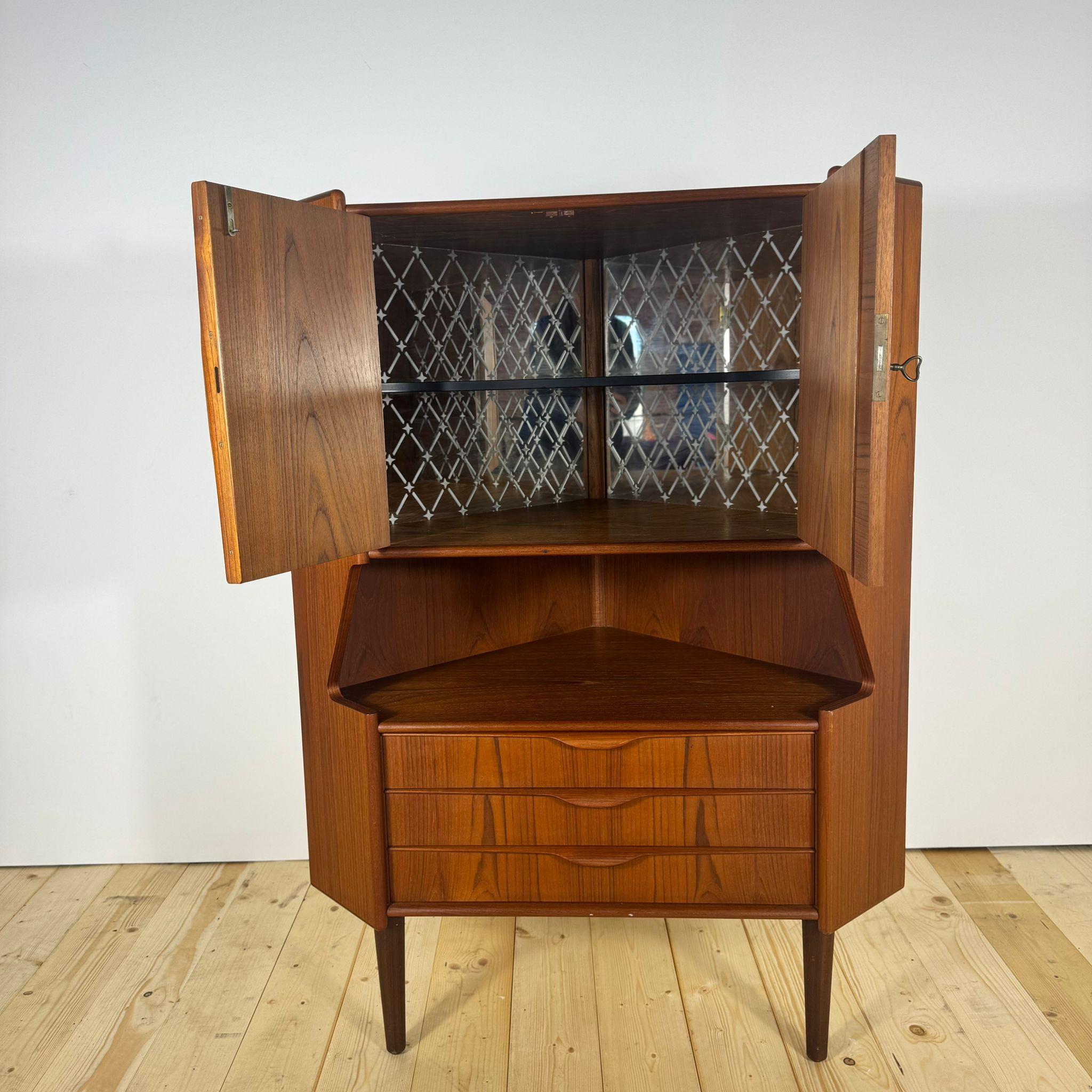 Questo raffinato mobile angolare in teak impiallacciato incarna la capacità del design scandinavo di unire estetica, funzionalità e intelligenza costruttiva. Progettato per sfruttare gli angoli della casa con eleganza, rappresenta un'autentica