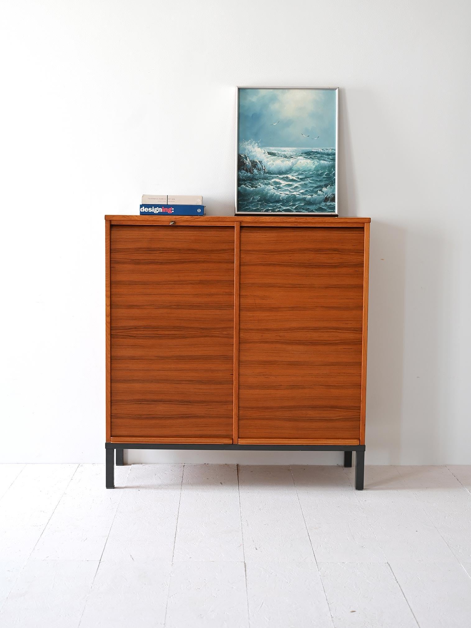 Storage cabinet with teak wood shutters, Swedish-made in the 1970s. Inside are office drawers.

Swedish 1970s archive made of teak wood, featuring sliding shutters. The solid structure rests on a black painted metal base. The interior is organized