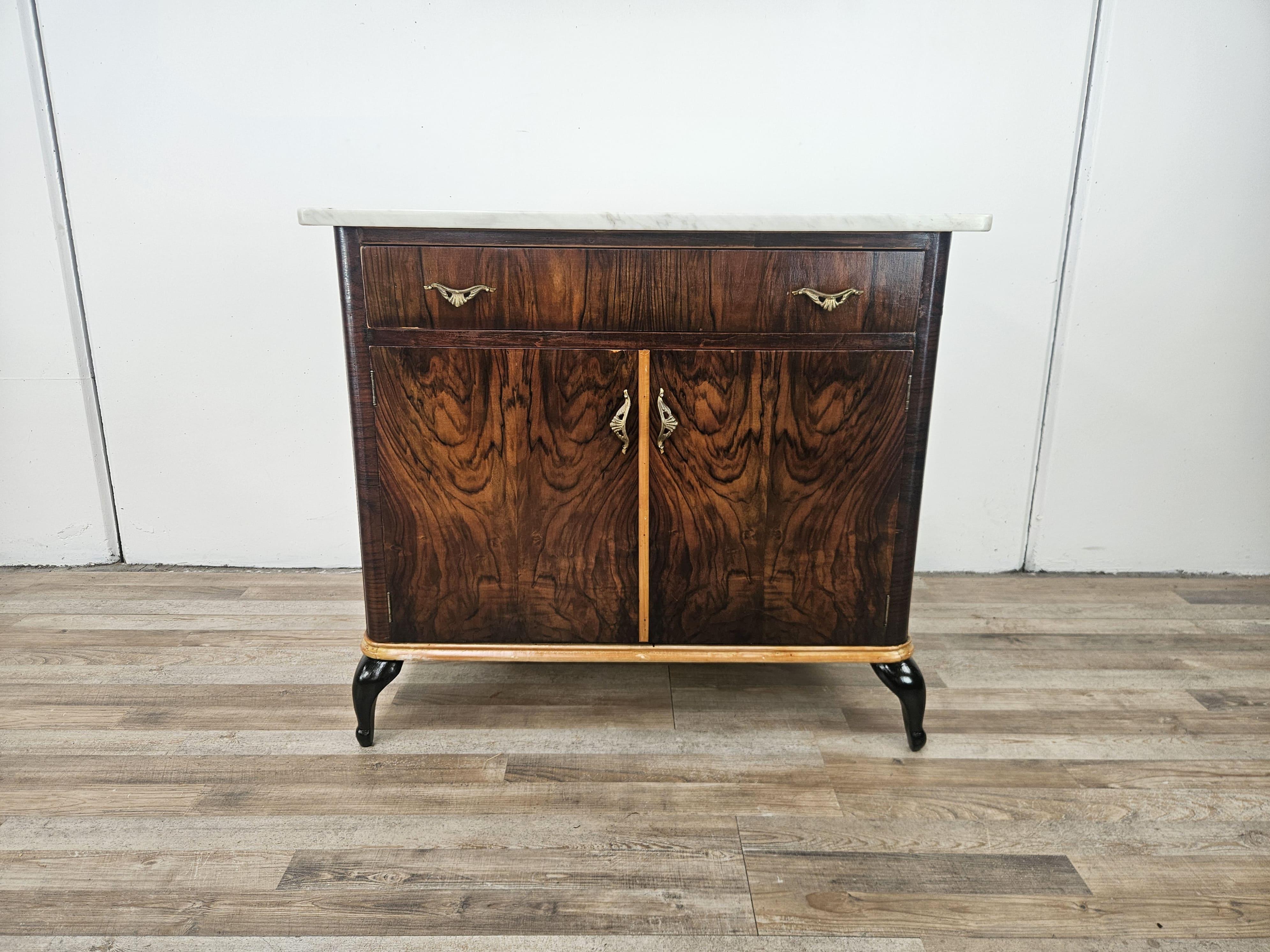 1950s Art Deco cabinet upholstered in mahogany burl with maple profiles and lacquered feet.

It can be used in different contexts, as a small dresser in the room or in the hallway and in different rooms.

The main top is an original white marble of
