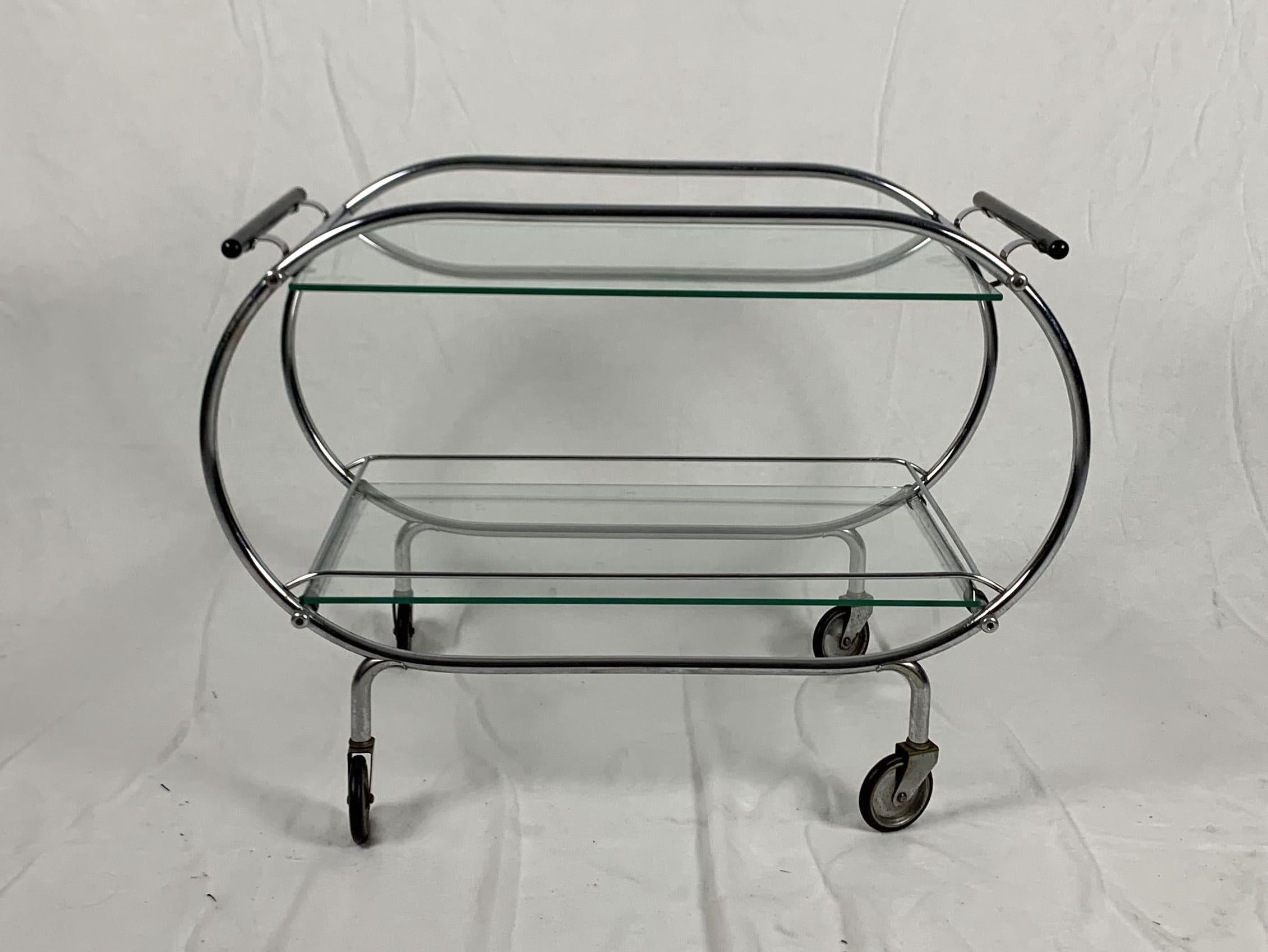 Art Deco / Bauhaus serving trolley / cart / mobile table from France, circa 1925.

Chromed tubular steeltube frame with original patina on 4 wheels. 
2 original glass shelves. Black lacquered wooden handles on two sides.

Dimensions: H 58 cm x