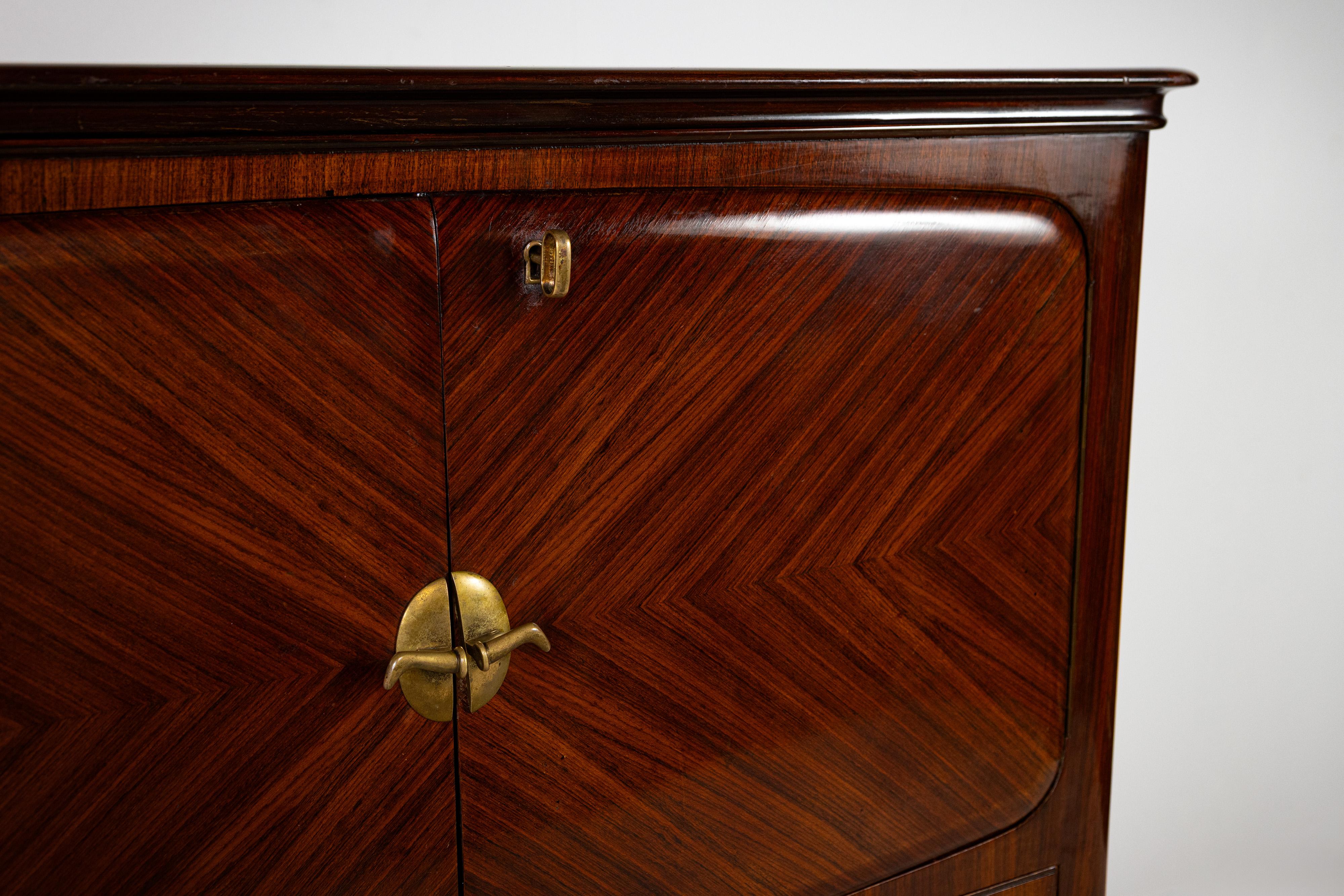 This refined 1950s bar cabinet, made in Italy, is a perfect blend of craftsmanship and timeless design. Constructed of fine wood, it stands out for its attention to detail, highlighted by elegant inlays that decorate surfaces with finesse. Expertly