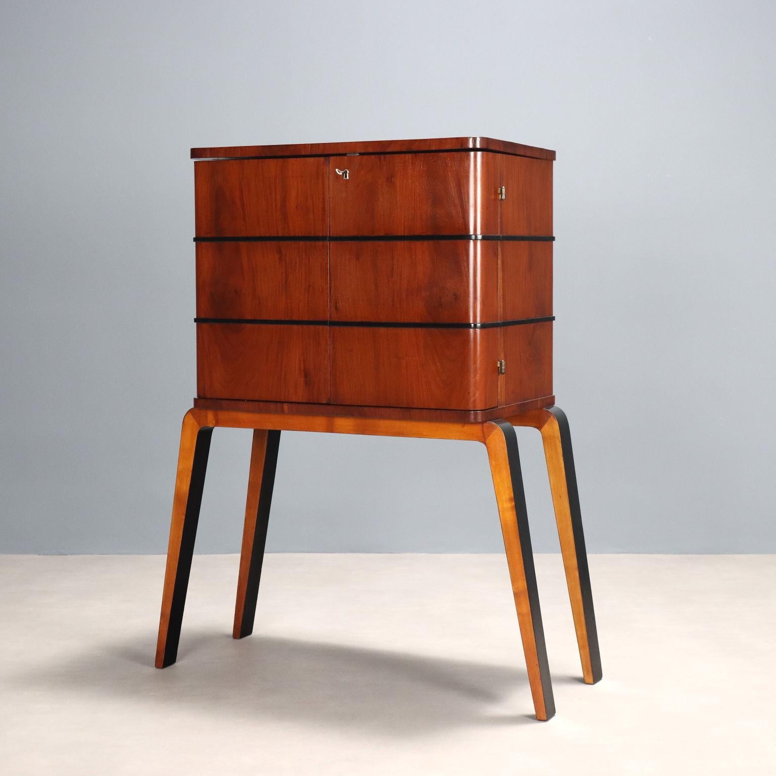 Elegant and stylish bar cabinet with hinged opening doors and opening top, poplar veneer interior with drawers and spaces for glasses, walnut veneer wood exterior with decorative horizontal lines in Ebony-stained wood, base with legs in natural and