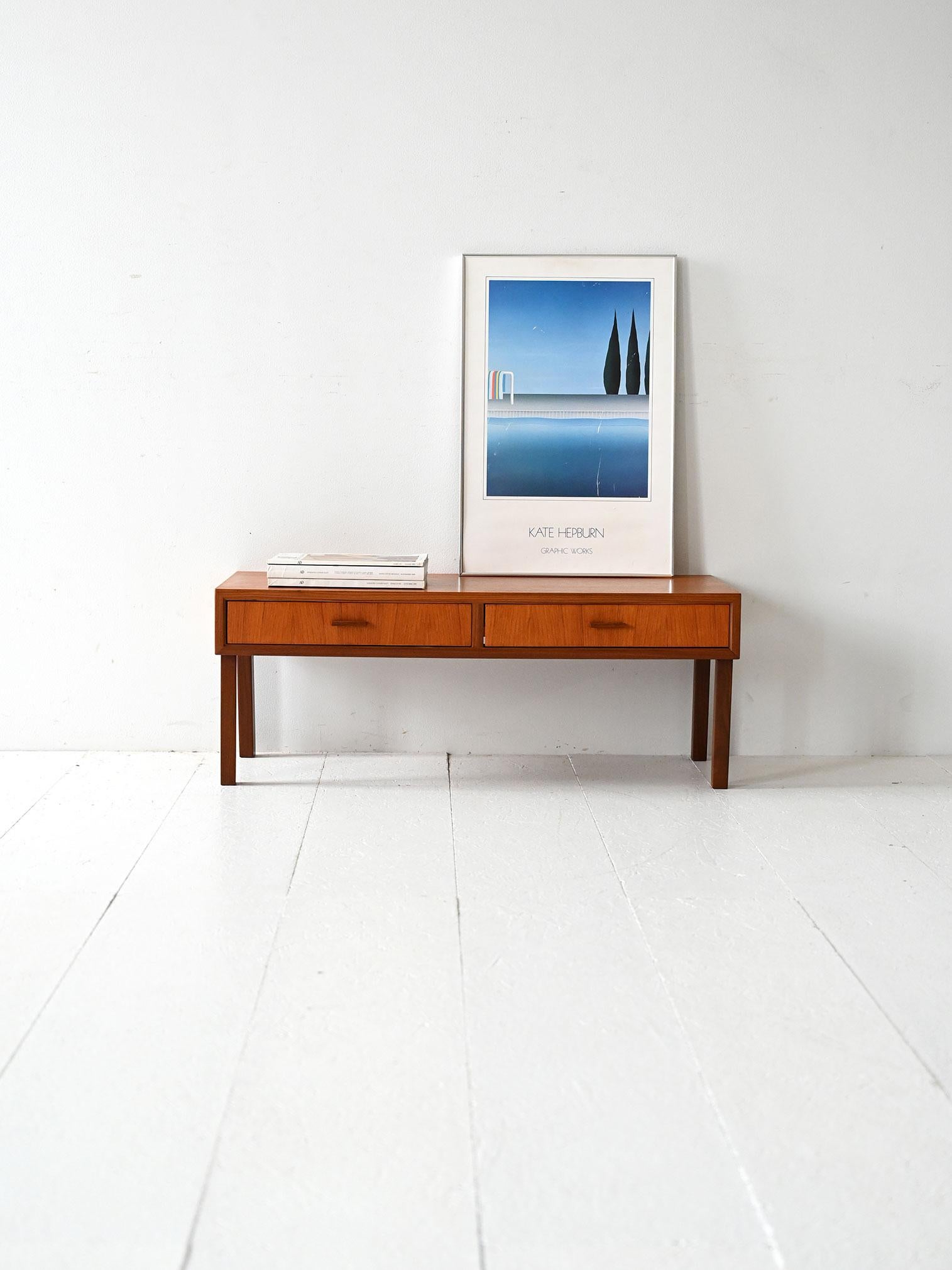 1960s teak entry cabinet with two drawers and carved handles.

Scandinavian 1960s teak low entry cabinet with linear frame and two front drawers. Carved handles and the contrast between the warm teak grain of the frame and the slightly darker teak