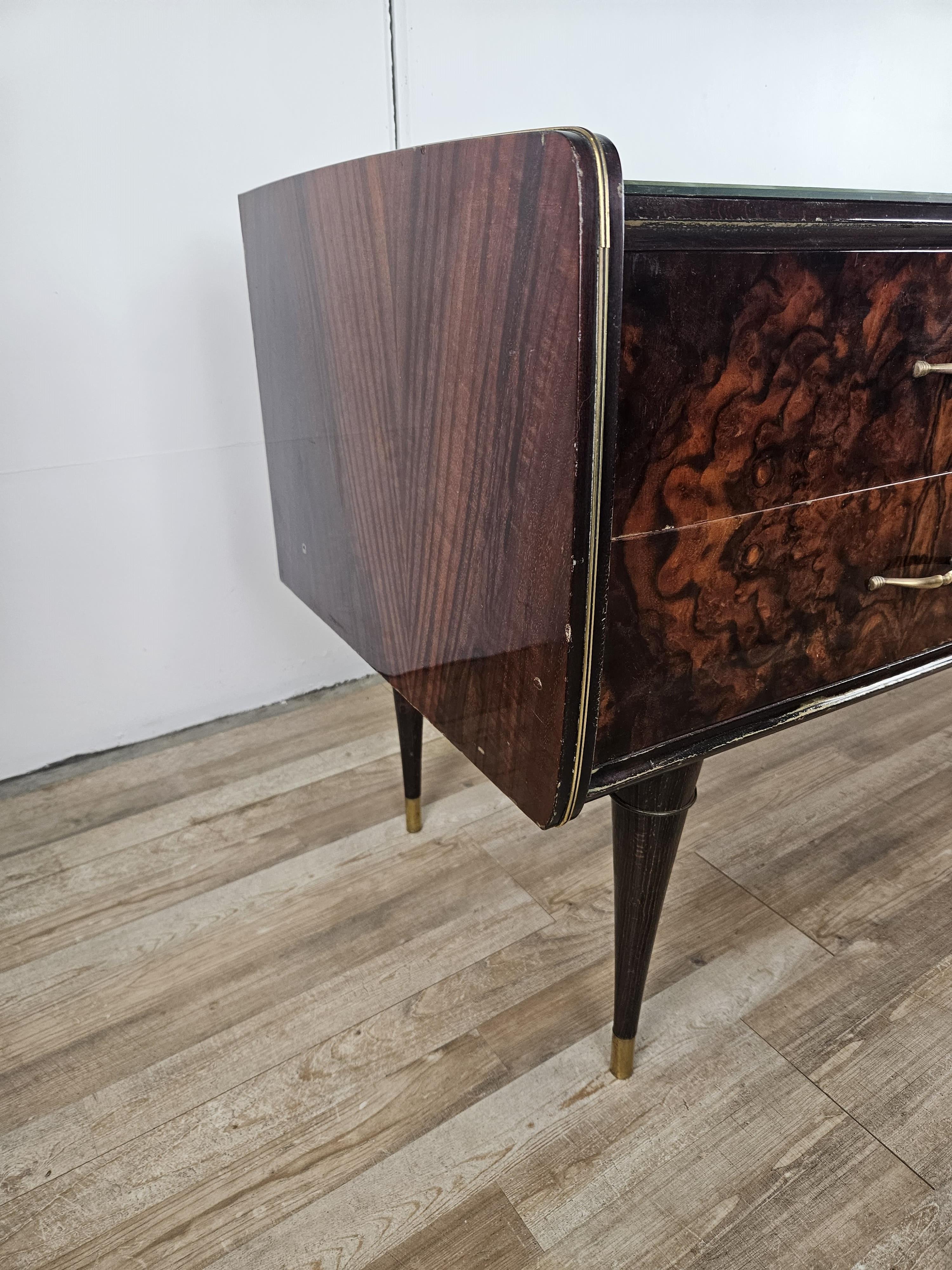 Mobile da camera o corridoio di produzione italiana anni '70 circa, arricchito da eleganti finiture in ottone e piano in vetro colorato e lavorato.

Il mobile si presenta con sei ampi cassetti e gambe a spillo.

Segni d'usura dovuti dall'età e