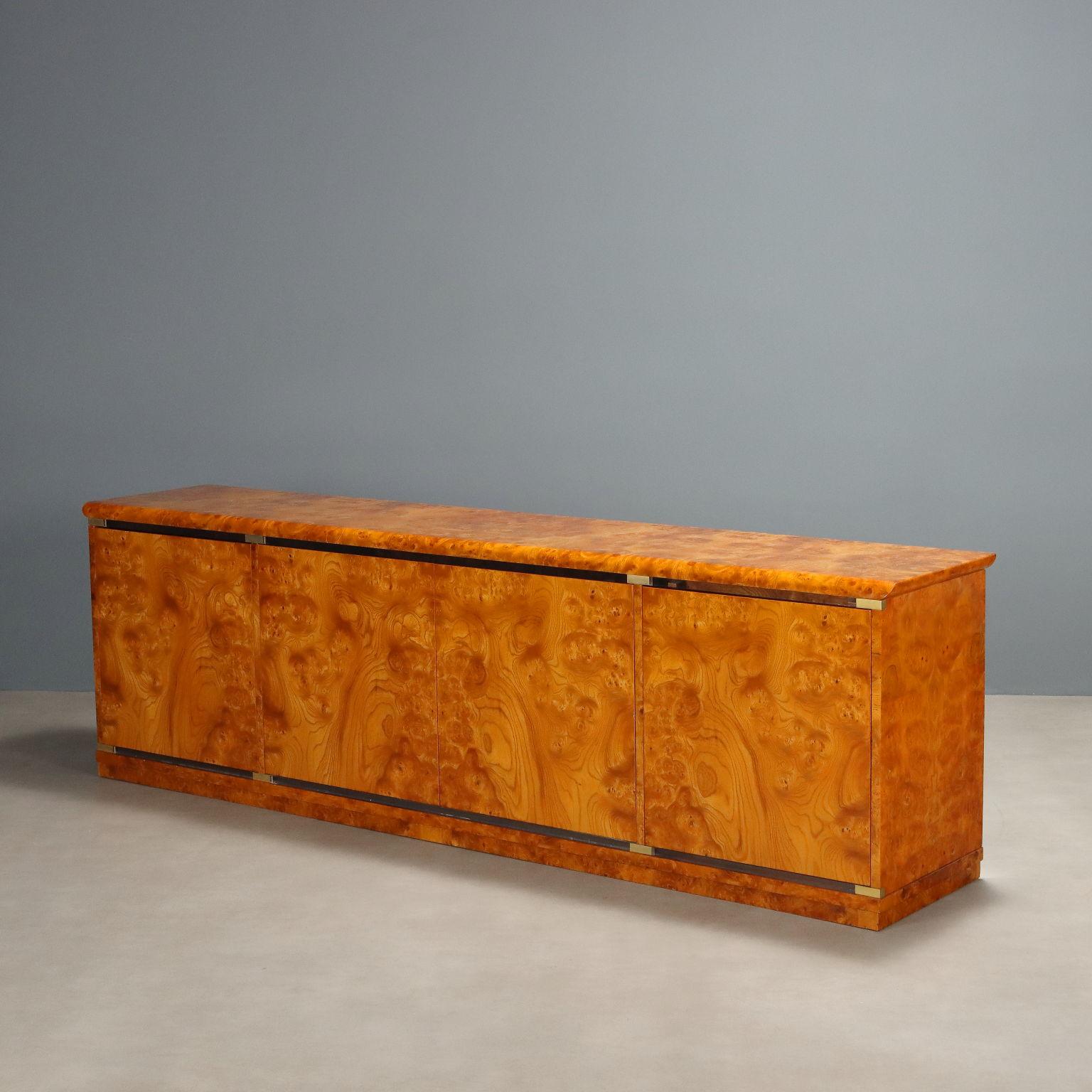 Mobil vintage da centro realizzato negli anni 70 con impiallacciatura in radica a finitura lucida con dettagli in ottone e inserti in materiale plastico trasparente. Presenta quattro ante a battente con apertura a spinta, all'interno cassetti e vani