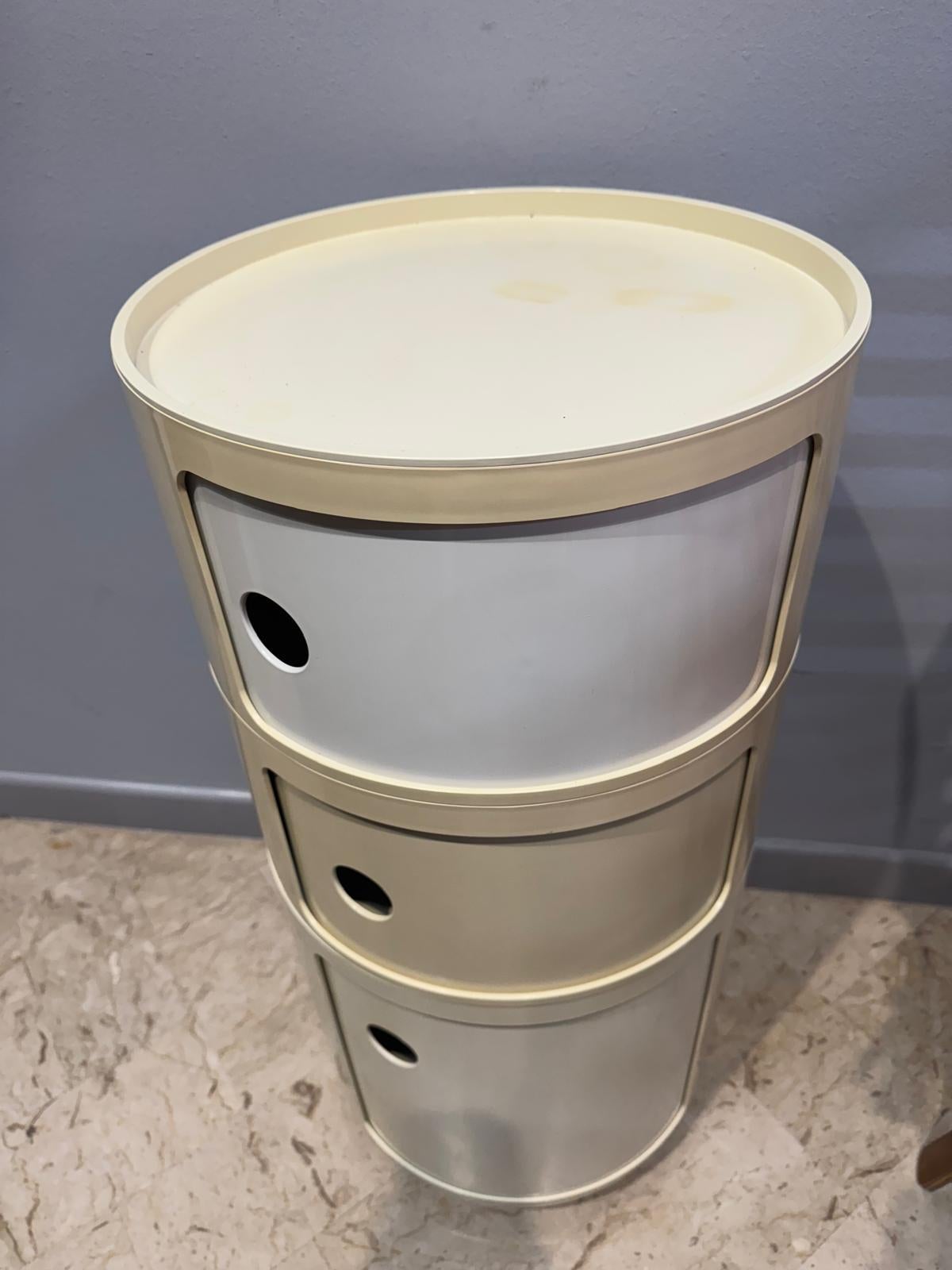 Questo iconico mobile è il Componibili di Kartell, un classico del design italiano creato da Anna Castelli Ferrieri nel 1967.
Si tratta di un sistema di moduli contenitori cilindrici realizzati in ABS plastico, progettati per essere funzionali,