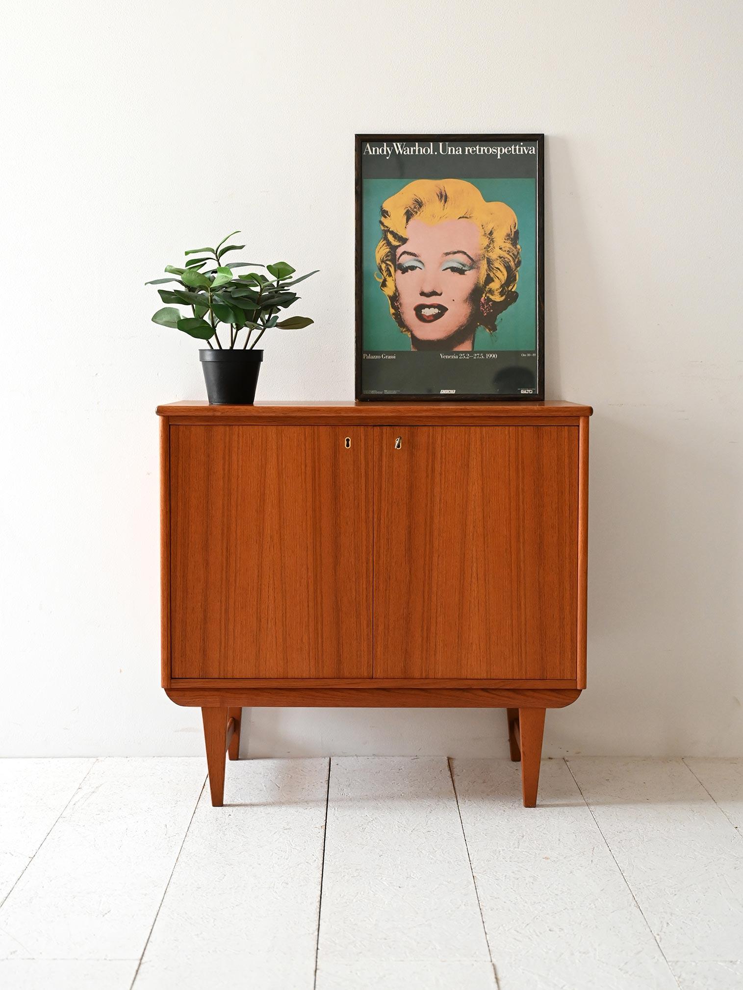Mobile vintage AB AJFA Möbelfabrik, in teak, due ante con serratura, mensola interna e gambe affusolate in stile scandinavo.

Mobile originale degli anni ’60 prodotto da AB AJFA Möbelfabrik a Tibro, Svezia. La struttura è in teak, con due ante