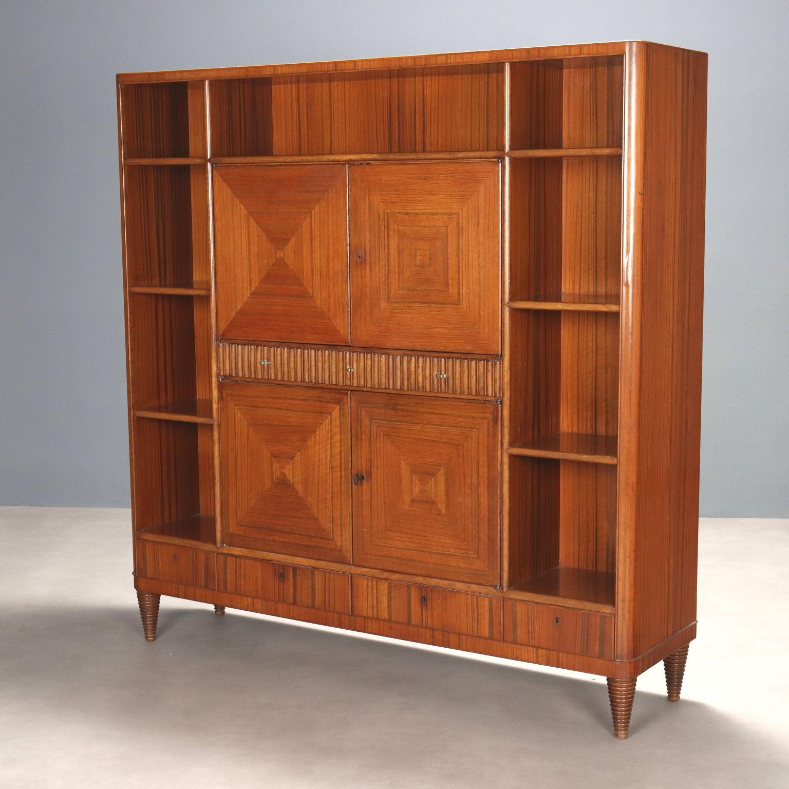 Aparador con puertas centrales batientes, compartimentos abiertos y cajones visibles. Madera chapada en madera exótica, interior cubierto de cristal espejado, frente de cajón con grissin, patas de madera torneadas cónicas.