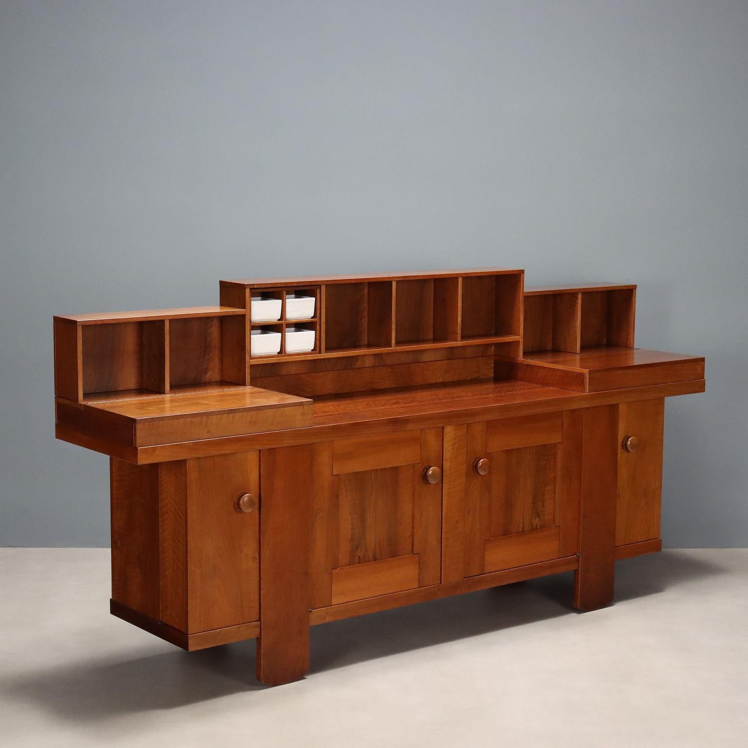 Aparador vintage de madera chapada en nogal con compartimentos abiertos completos con cerámica original de la marca Bernini, y puertas abatibles debajo.