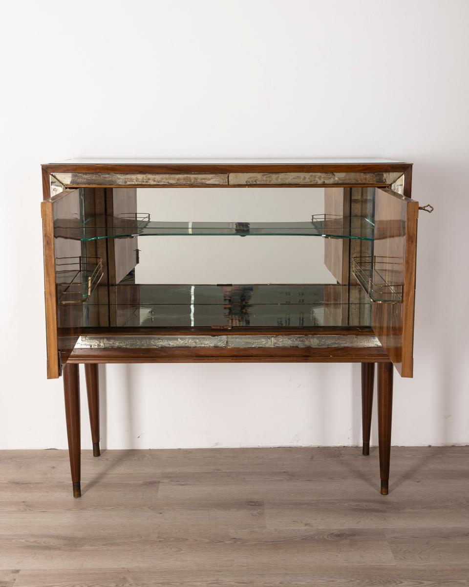 Walnut bar cabinet with decorated glass and mirrors, interior lined with mirrors and glass top, 1950s.

CONDITION: In good condition, shows signs of wear given by time.

DIMENSIONS: Height 109 cm; Width 112 cm; Length 40.5 cm

MATERIALS: Wood and