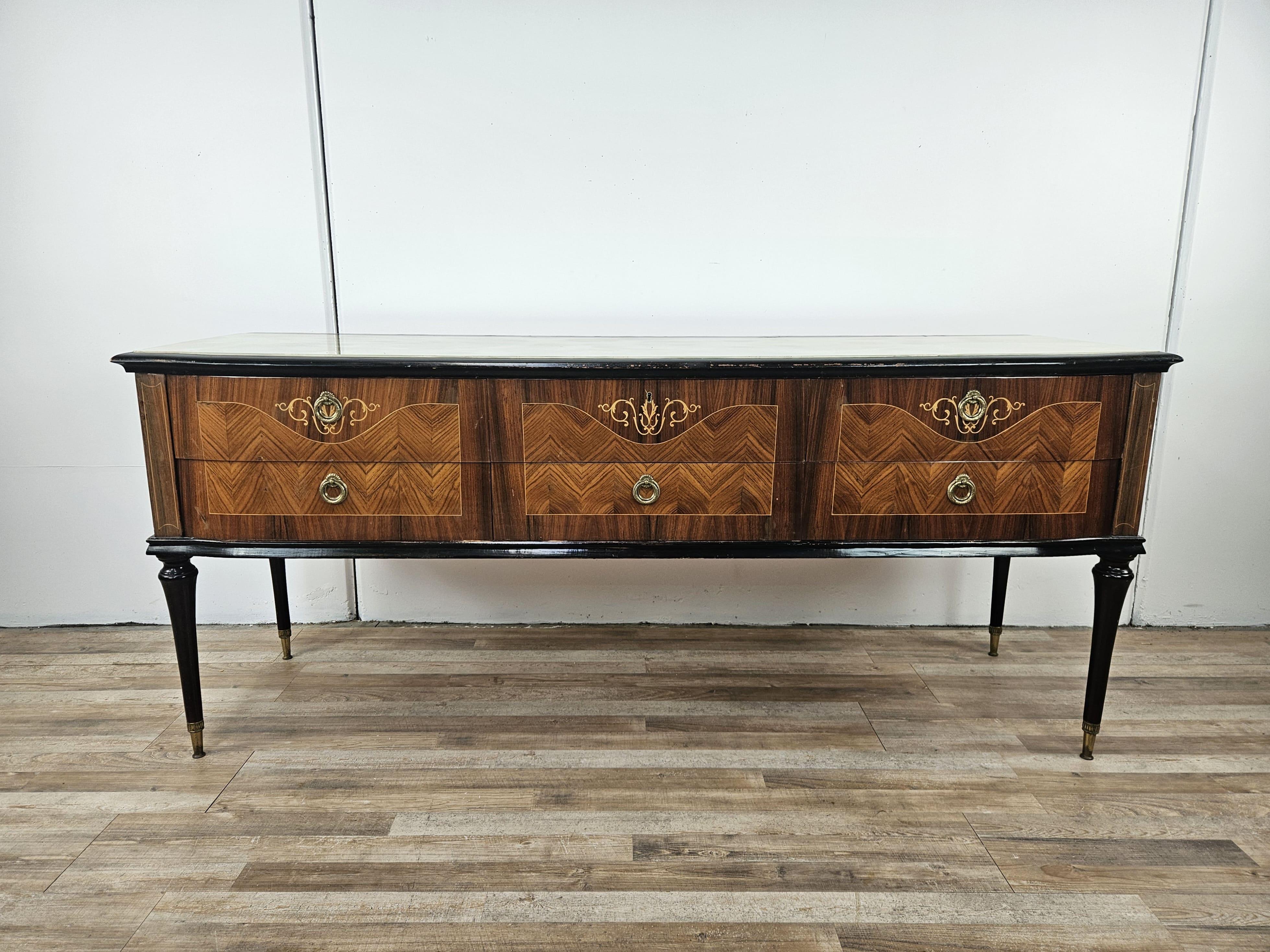 Bedroom chest of drawers with large and sturdy drawers, decorated on the front and further enhanced by a beautiful stained and decorated glass top.

High wooden and brass legs.

The cabinet shows normal signs of wear and tear due to age and use as