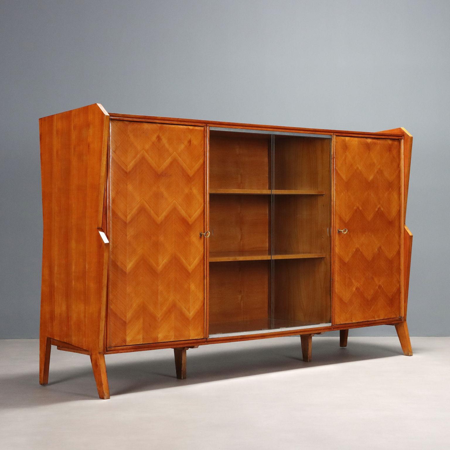 Arredo vintage di manifattura italiana del XX secolo con ante a battente e vetrina centrale con ripiani. Realizzato in legno con impiallacciature in legno esotico.