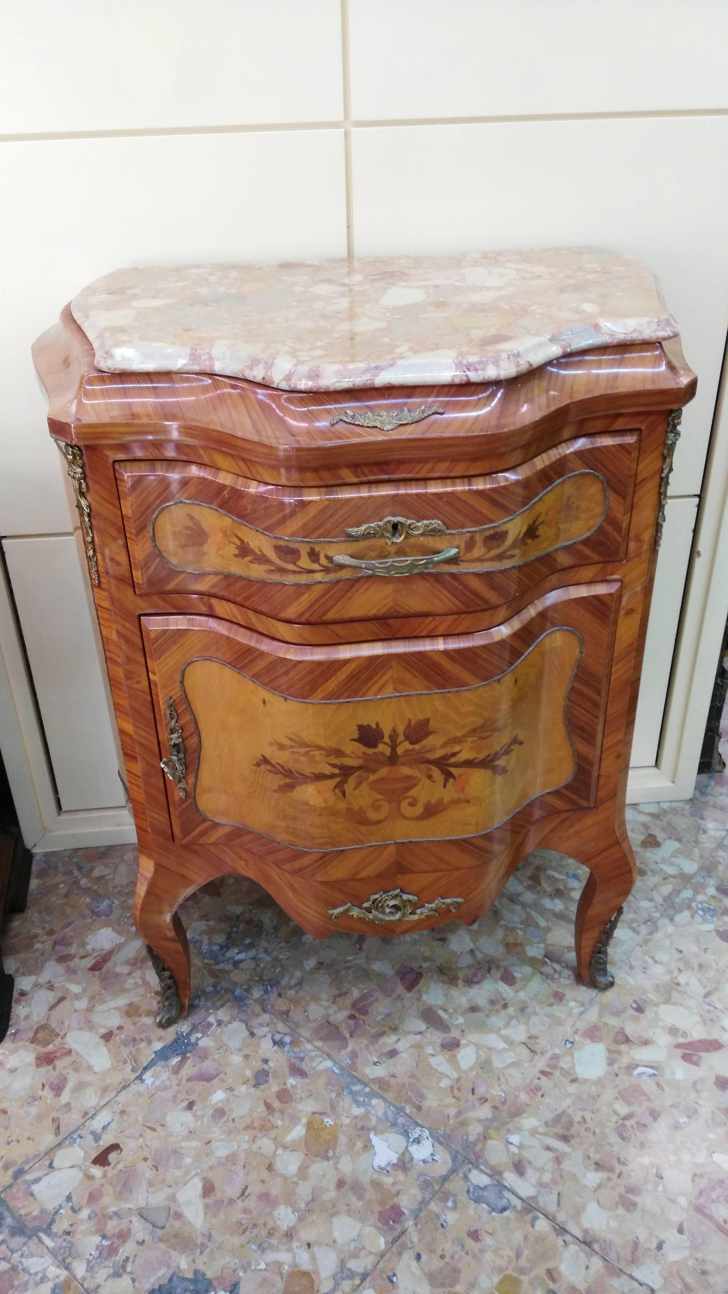 Veneered in various woods, with applications in gilded bronze, front with a central door embellished with embossed relief in golden metal, marble top.