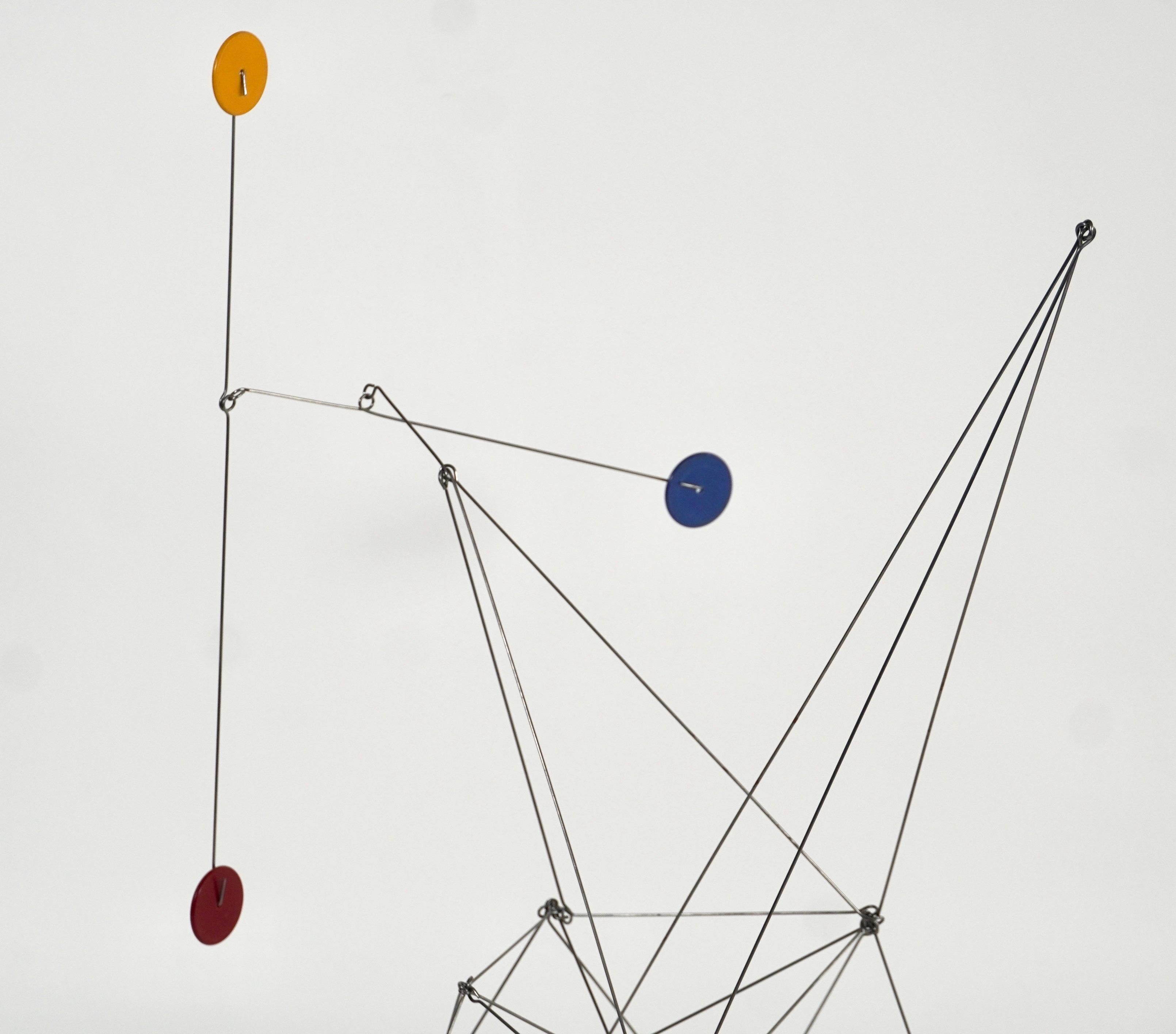 Wire mobile / kinetic sculpture by California artist Dan Levin with a complicated array of wire connections for the main body of the sculpture with a mobile arm with 3 colorful discs that are counterbalanced and move freely when touched.