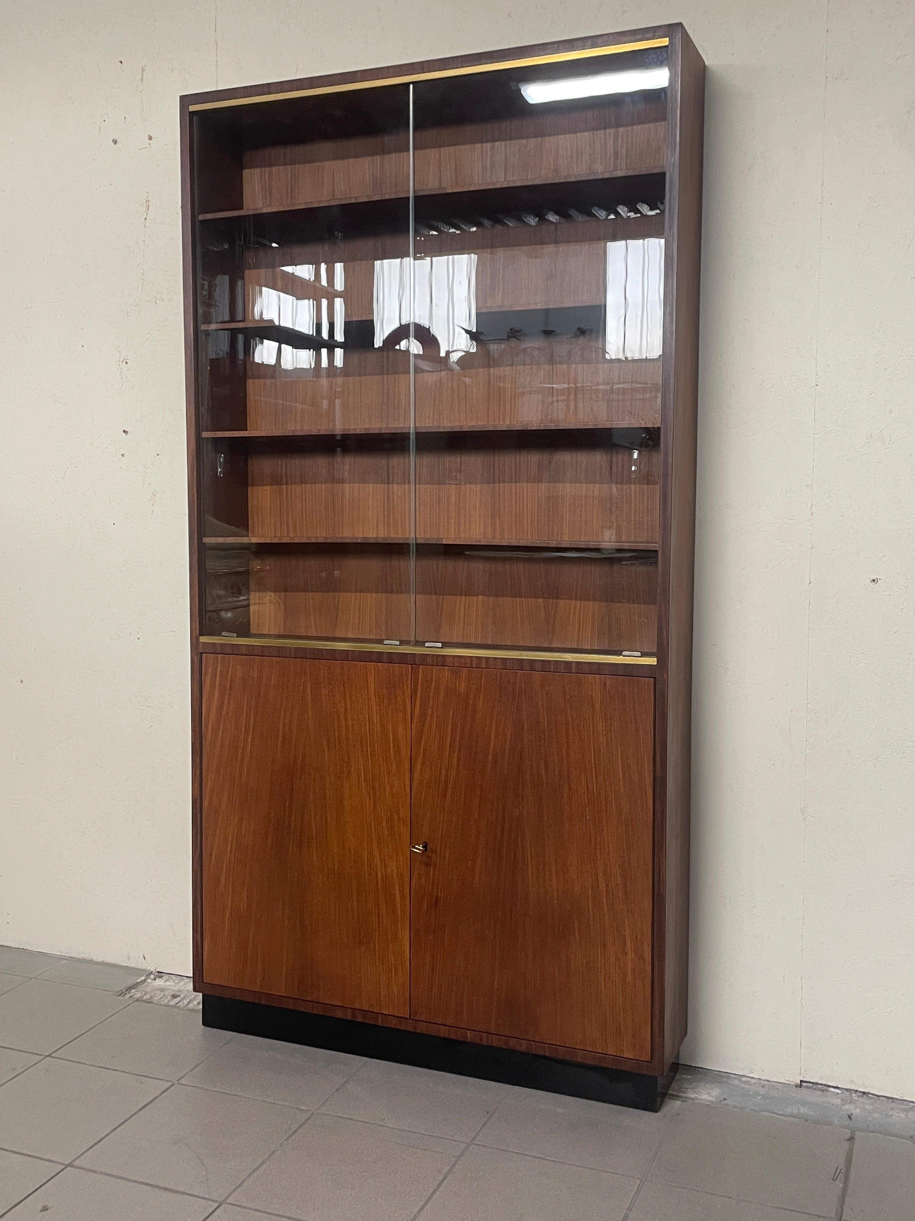 1960s teak wood bookcase / display cabinet.

The upper part consisting of 4 shelves and closed by 2 sliding glass doors.

The lower part, two wooden doors close the two inner shelves.

Cabinet ideal as a small bookcase or display cabinet due to its