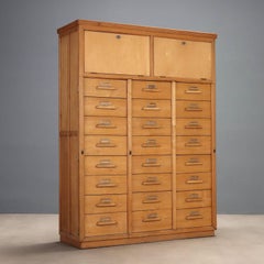 A wooden filing cabinet from the 1950s with numerous drawers.