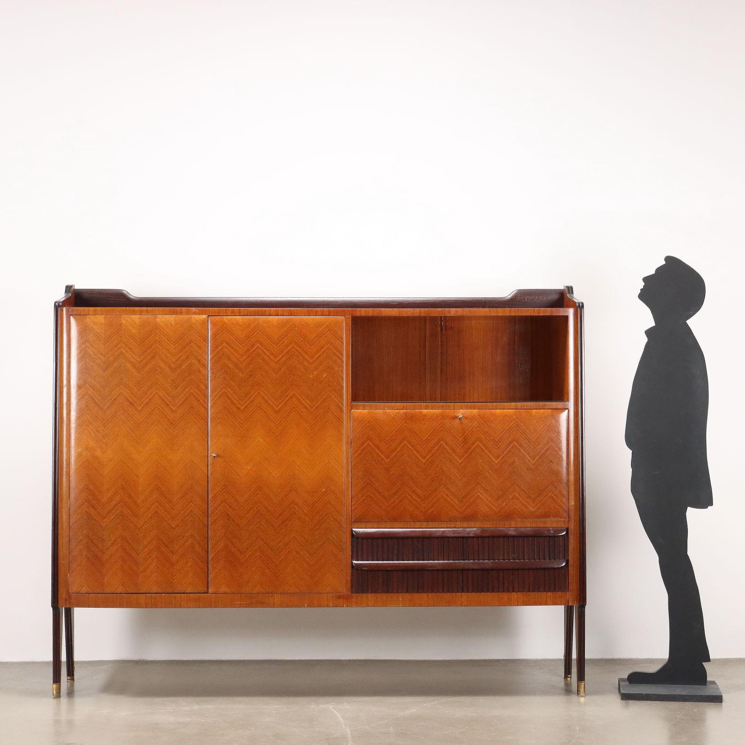 Vintage furniture of 20th-century Italian manufacture with hinged doors, open compartments, flap containing a bar compartment with glass shelf and glass bottom, pair of drawers with grissinated front. Made of exotic wood veneer and stained wood.