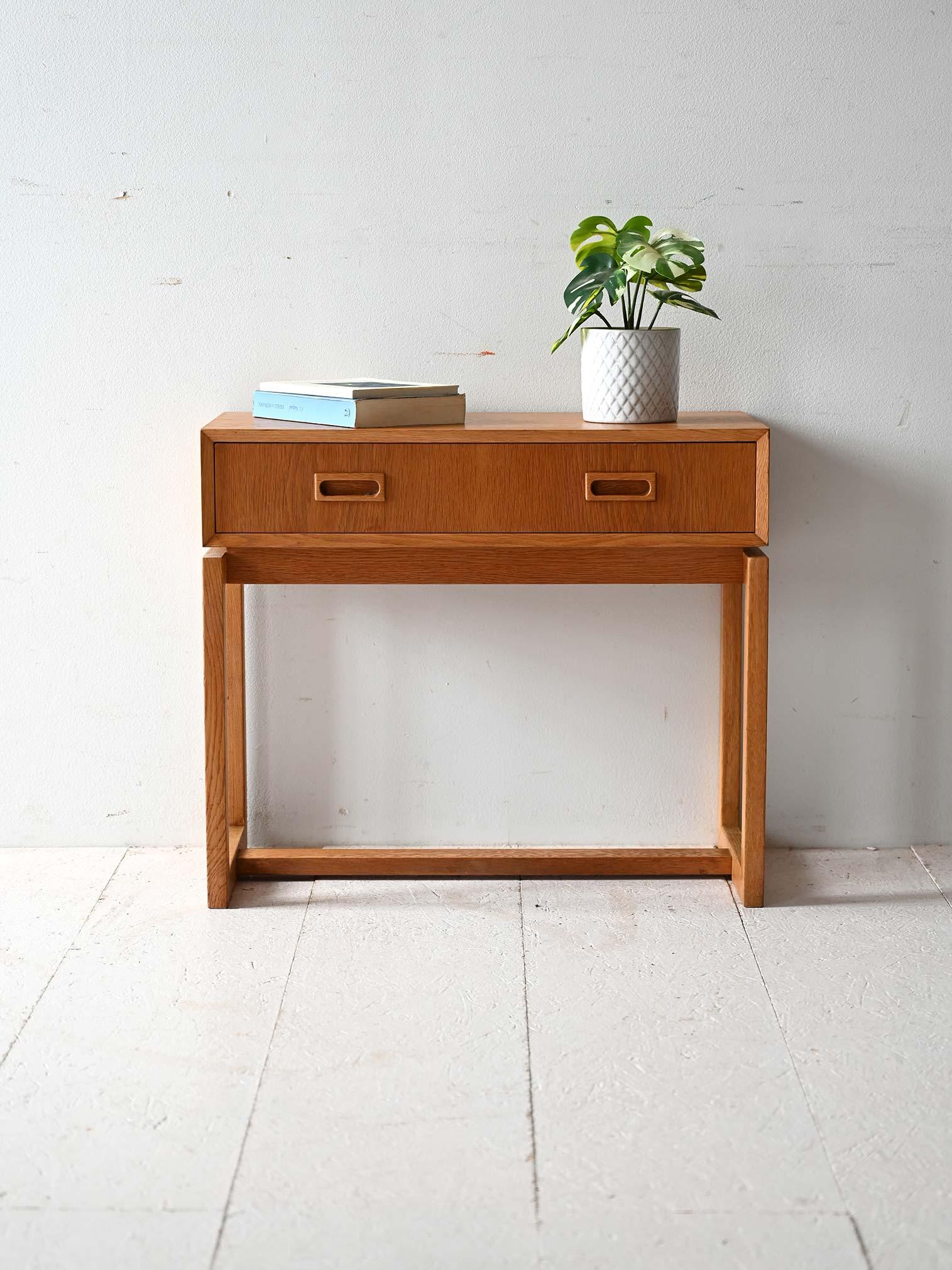 Scandinavian design with geometric structure, two drawers and orthogonal carved handles.

Scandinavian 1960s oak entry cabinet with two front drawers fitted with orthogonal carved handles. The compact and functional upper volume is lightened by the