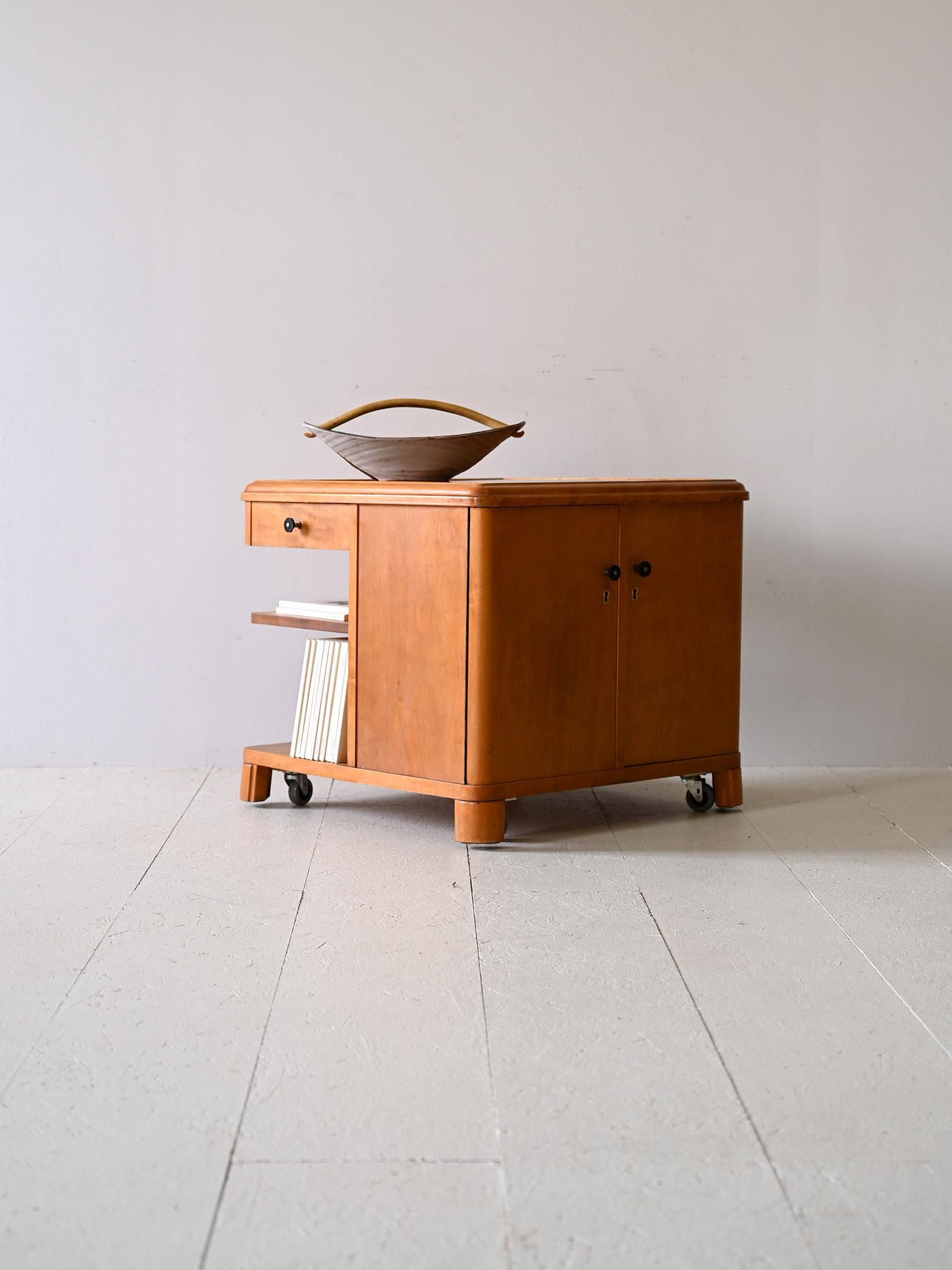 Coffee table with compartments and bookcase produced in Scandinavia in the 1940s.

Original Deco trolley cabinet made of birch wood.
Equipped with lockable hinged doors, a drawer and shelves for organizing books and objects, this trolley cabinet is