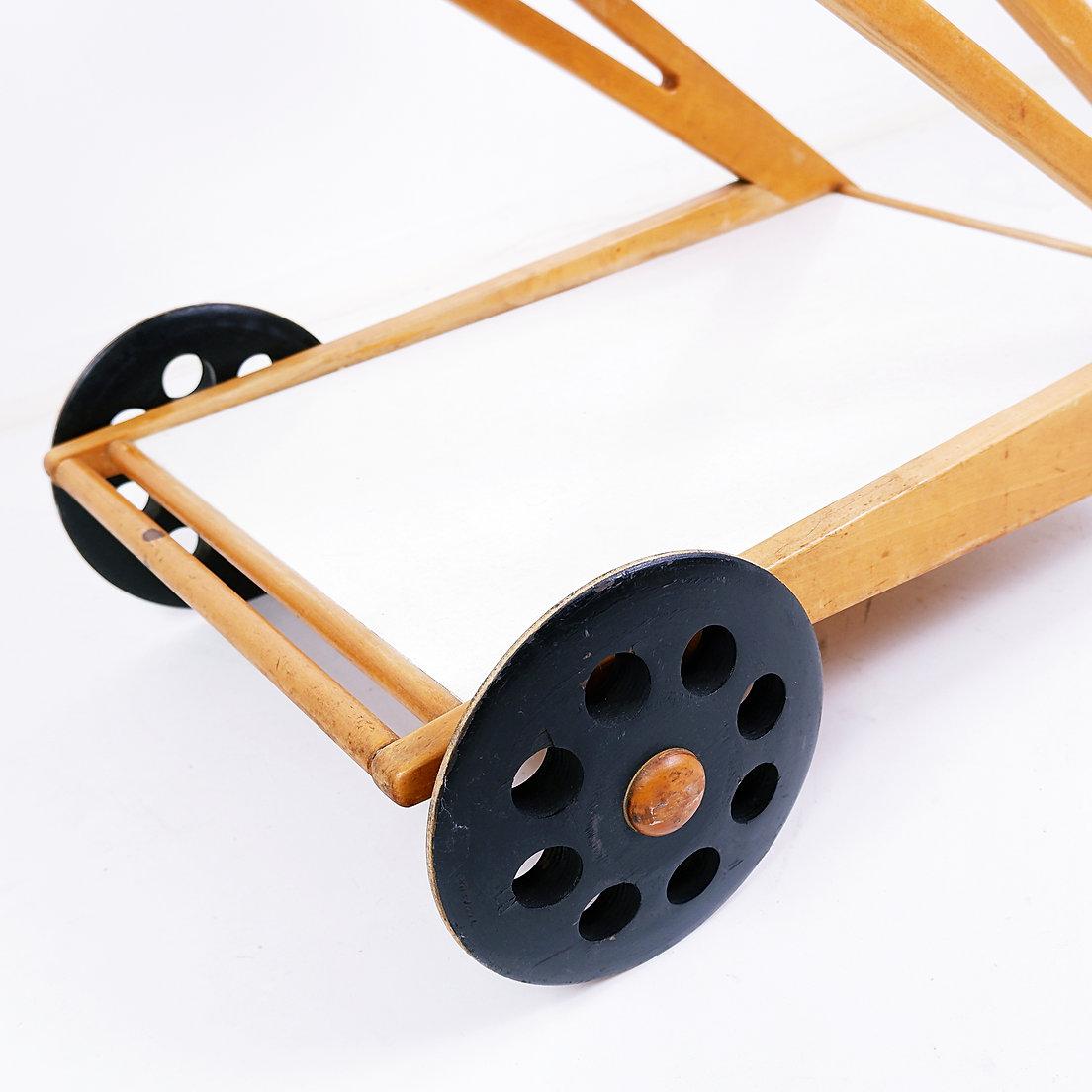 Elegant and hard to find trolley. Maple/oak wooden Z-shaped frame with two laminated trays. The top tray can slide open and/or removed with a small wooden serving basket underneath. Black ebonized wheels back and small rotating wheels at front.
Wear