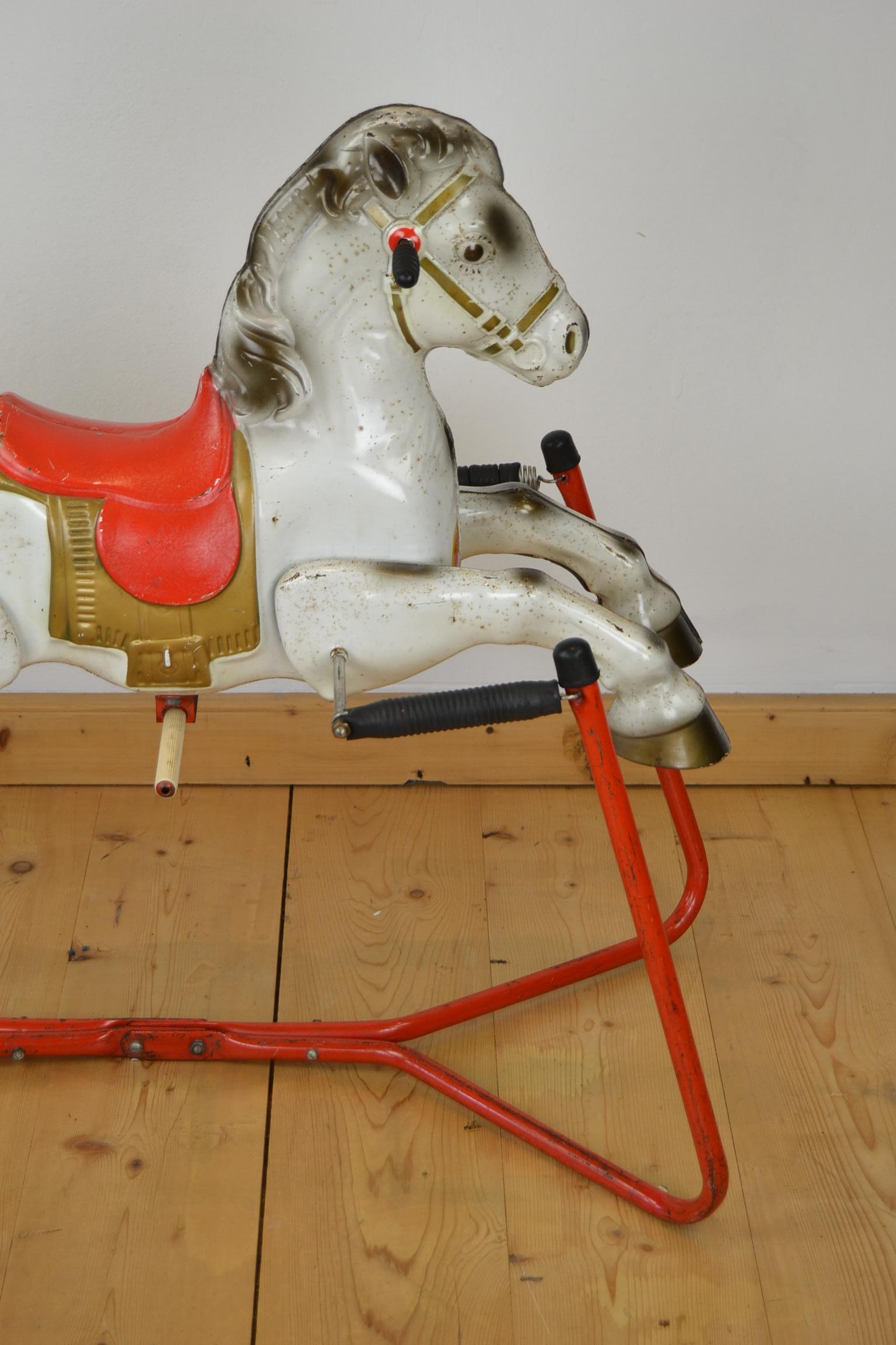 1960s Mobo Prairie King Rocking Horse Toy. This Rocking Horse was made in England by D.Sebel & Co LTD Mobo Toys. This metal horse toy is standing on a frame with springs to rock. With a red saddle and a gold colored saddle cloth or caparison. Made
