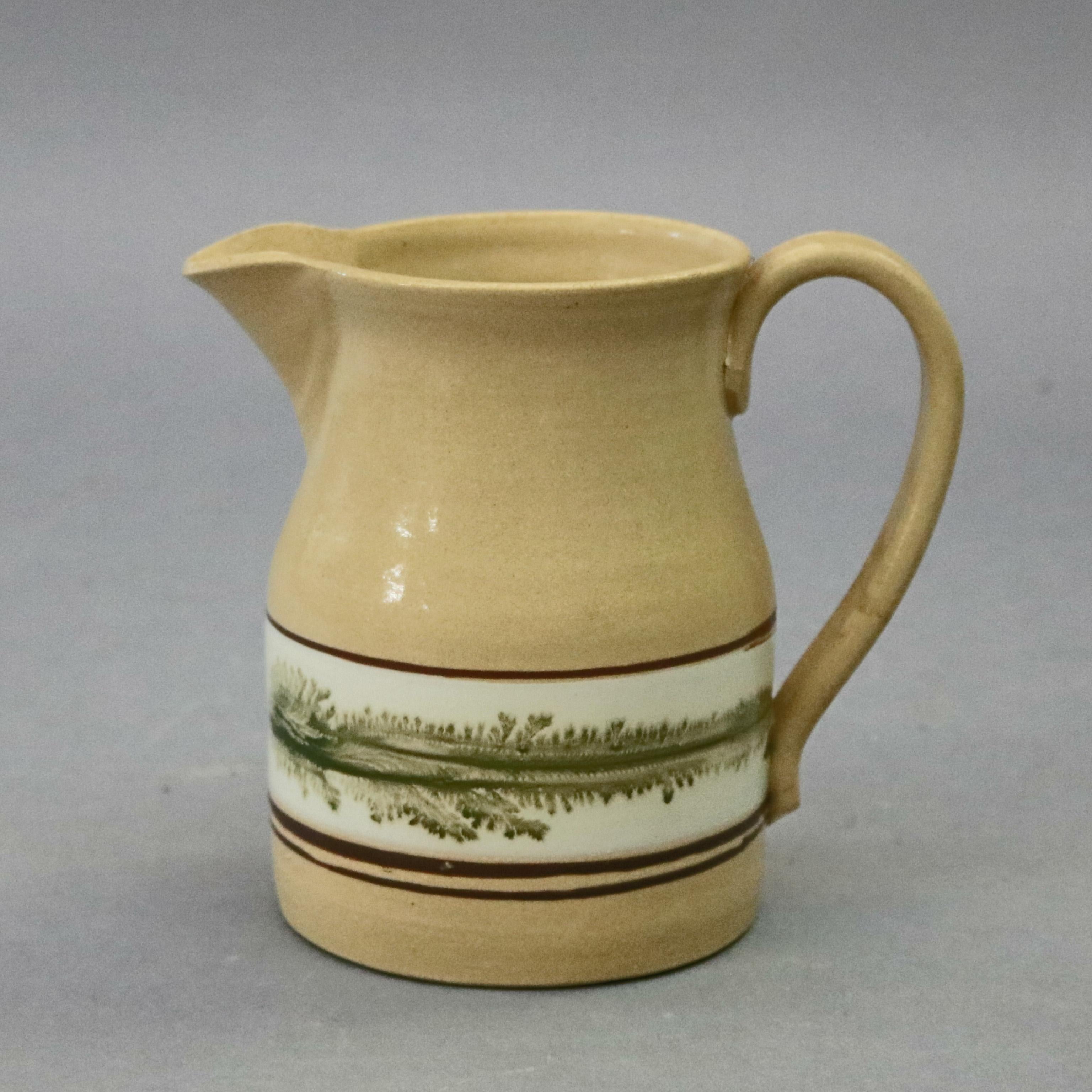 Mocha yellow ware batter (or water) pitcher by East Knoll Pottery features flared lip and spout with band of feathered decoration, maker mark impressed in base as photographed, 20th century


Measures: 6.5