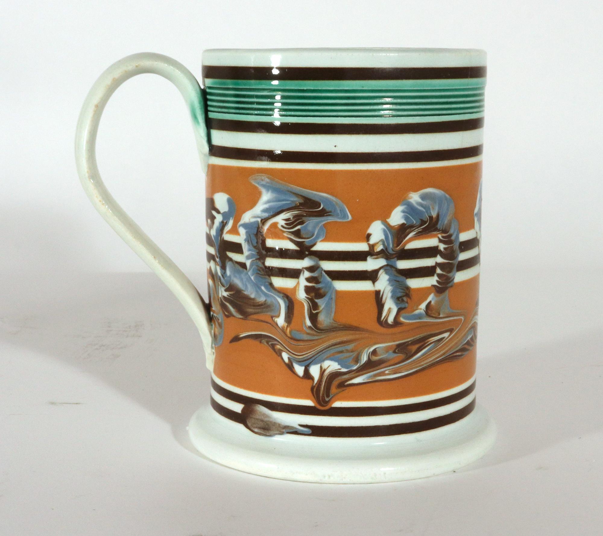 Mocha Pearlware Large Earthworm Tankard,
Circa 1800

The large pearlware Mocha tankard is decorated with a looping tri-color earthworm design around the center on an ochre-colored ground.  The tankard has a wide flaring foot and three groupings of