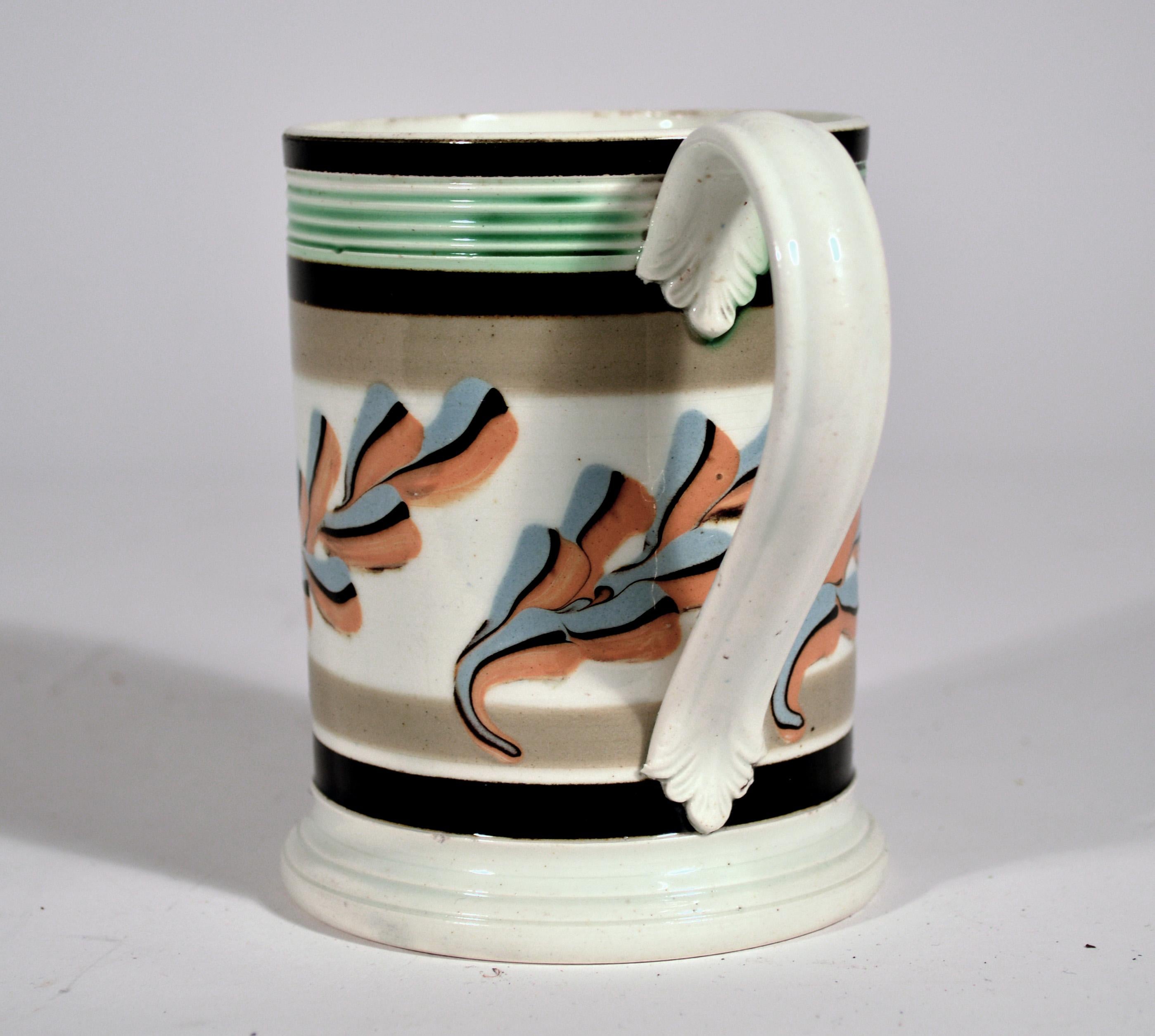 Mocha Mug with Oak Leaf Decoration,
Circa 1800

The pint mocha mug with slip decoration of oak leaves against a white background bordered by bands of gray and black slip and with a green-glazed reeded rim. The applied extruded handle with foliate