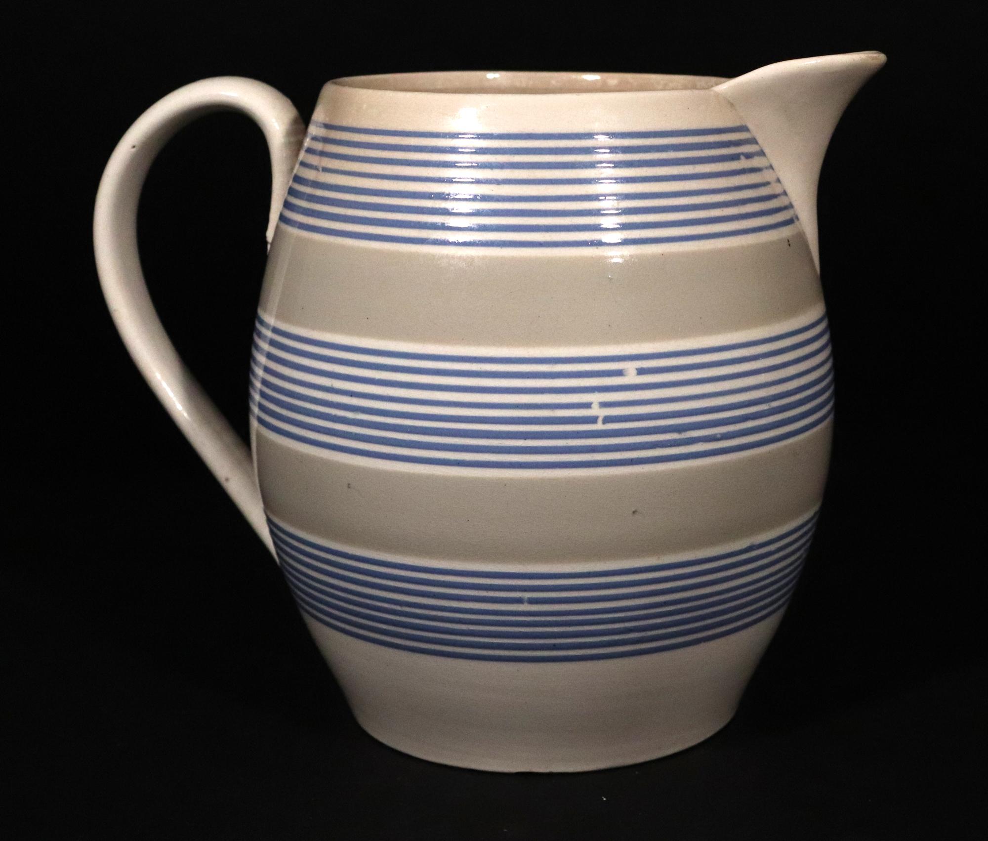 Mocha Slip-dekorierte große Keramik gebändert Krug,
CIRCA 1810-20

Der runde, große Mokka-Krug aus Perlware ist mit zwei hellgrünen/grauen Bändern verziert, die von drei weißen Bändern mit jeweils acht blauen, dünnen Linien unterbrochen werden.

Der