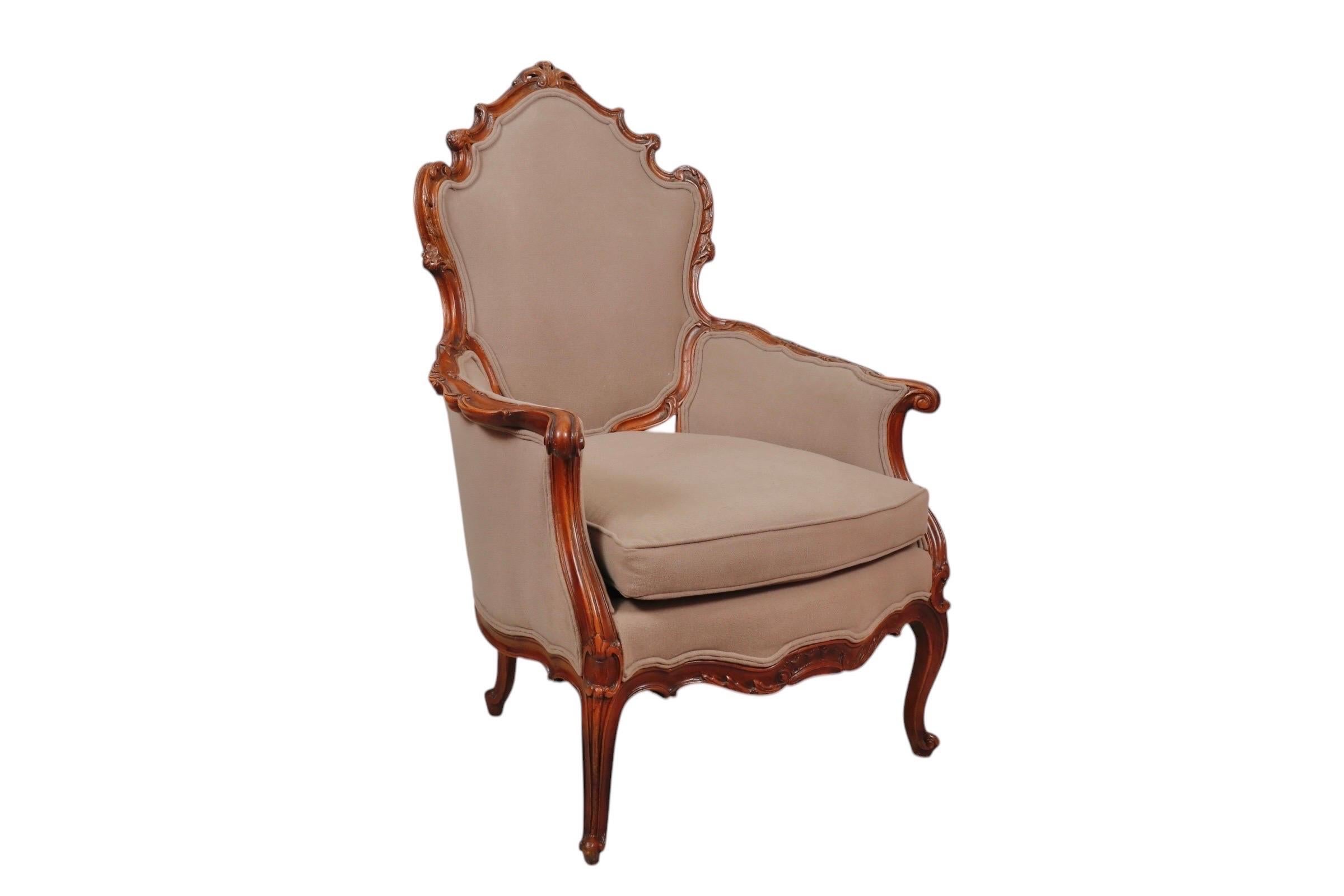 A hand carved Rococo bergere armchair circa 1890. The solid frame is elegantly carved with serpentine curves, detailed with c-scrolls, acanthus leaves and rosettes throughout. The high back is topped with a pierced crest rail and flows into outward
