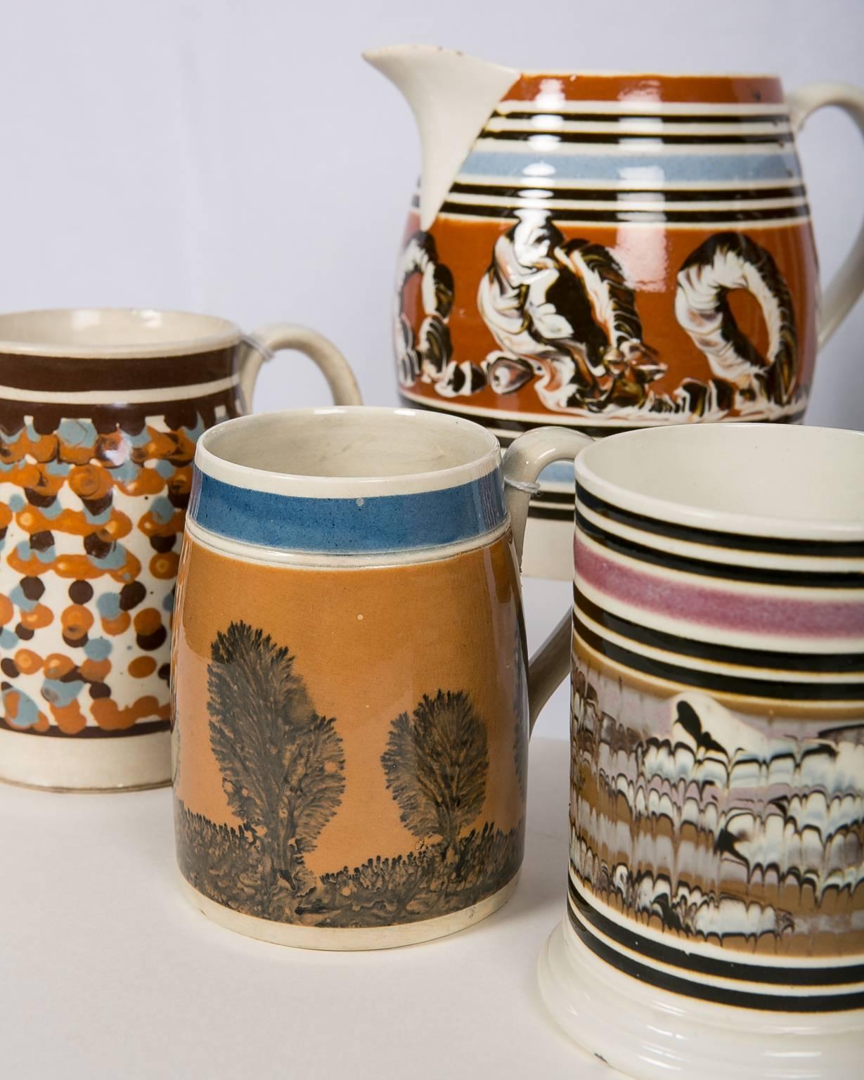 A collection of outstanding English Mochaware mugs and pitchers. The four mugs and three pitchers represent a variety of design which shows the individuality of Mochaware. Every piece of Mochaware is unique. Each piece is strikingly different, but
