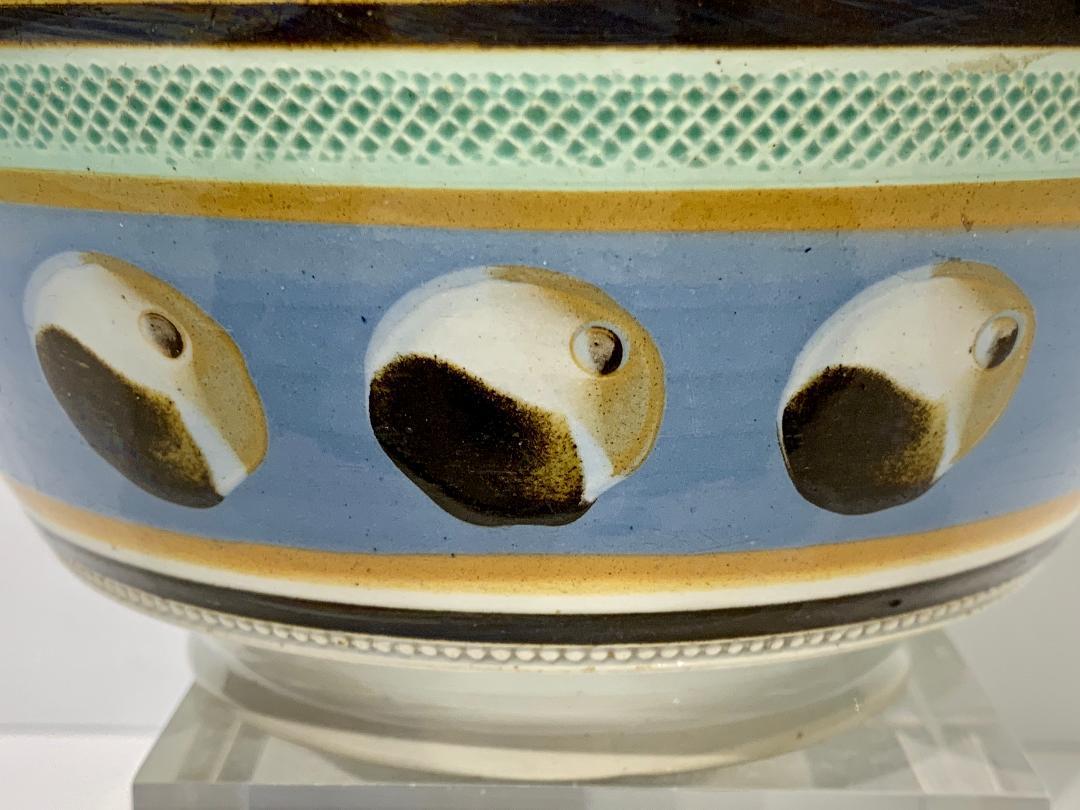 Mocha ware bowl with cat's eye decoration, England, circa 1820
The bowl has green glazed rouletting, broadband of blue slip and thinner bands of light and dark brown slip. The blue band is decorated with a three-color cat's eye design.
Dimensions: