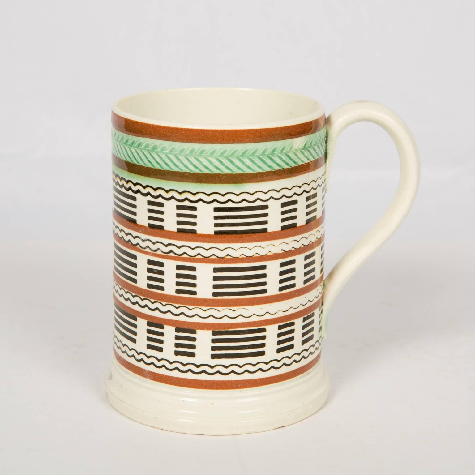 Provenance:
Mr. and Mrs. Jerome Blum
Russell Scheider Antiques

A pearlware half pint mug decorated with double bands of light brown slip and a band of green glazed herringbone rouletting at the mouth. Further decorated with straight and wavy